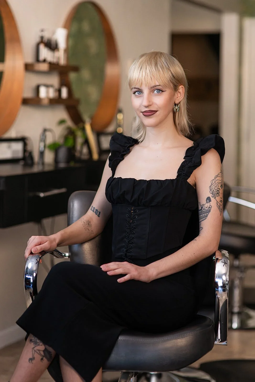 Irelan- A woman with blonde hair, blue eyes, and dark lipstick sitting in a salon chair.