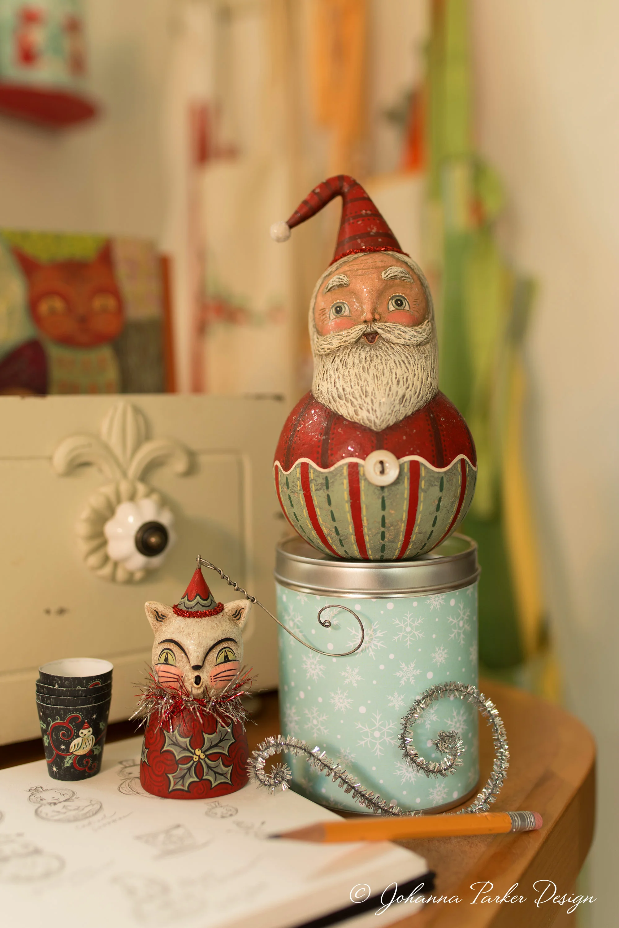 A wall nook of my hanging aprons creates a soft backdrop for my jolly ball-shaped Santa and winter kitty ornament bell. 