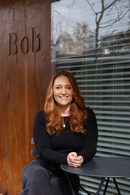 woman sitting at table and chair in front of wooden door at bob hair co.