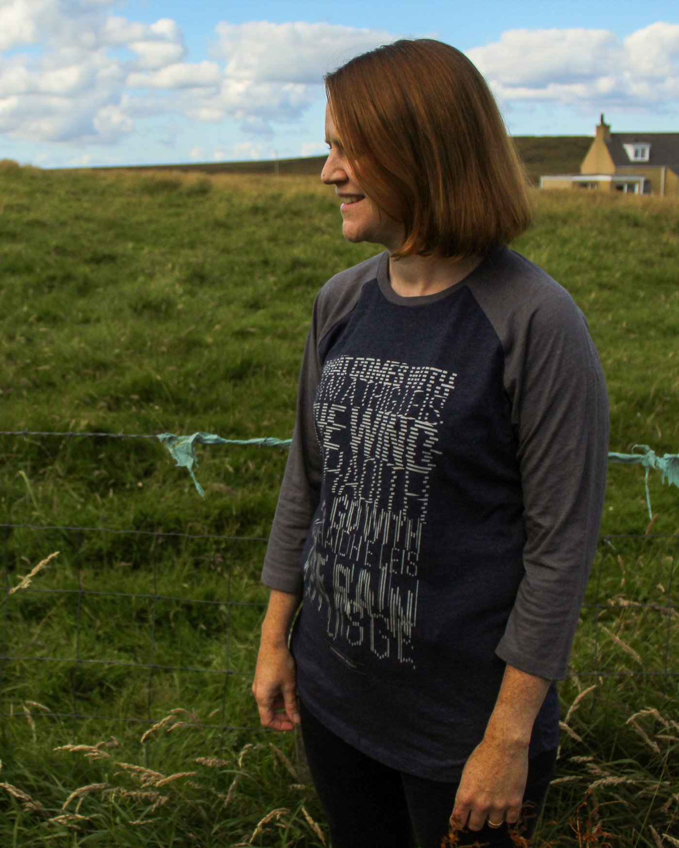 A woman in a field in the Outer Hebrides wearing a graphic design t-shirt
