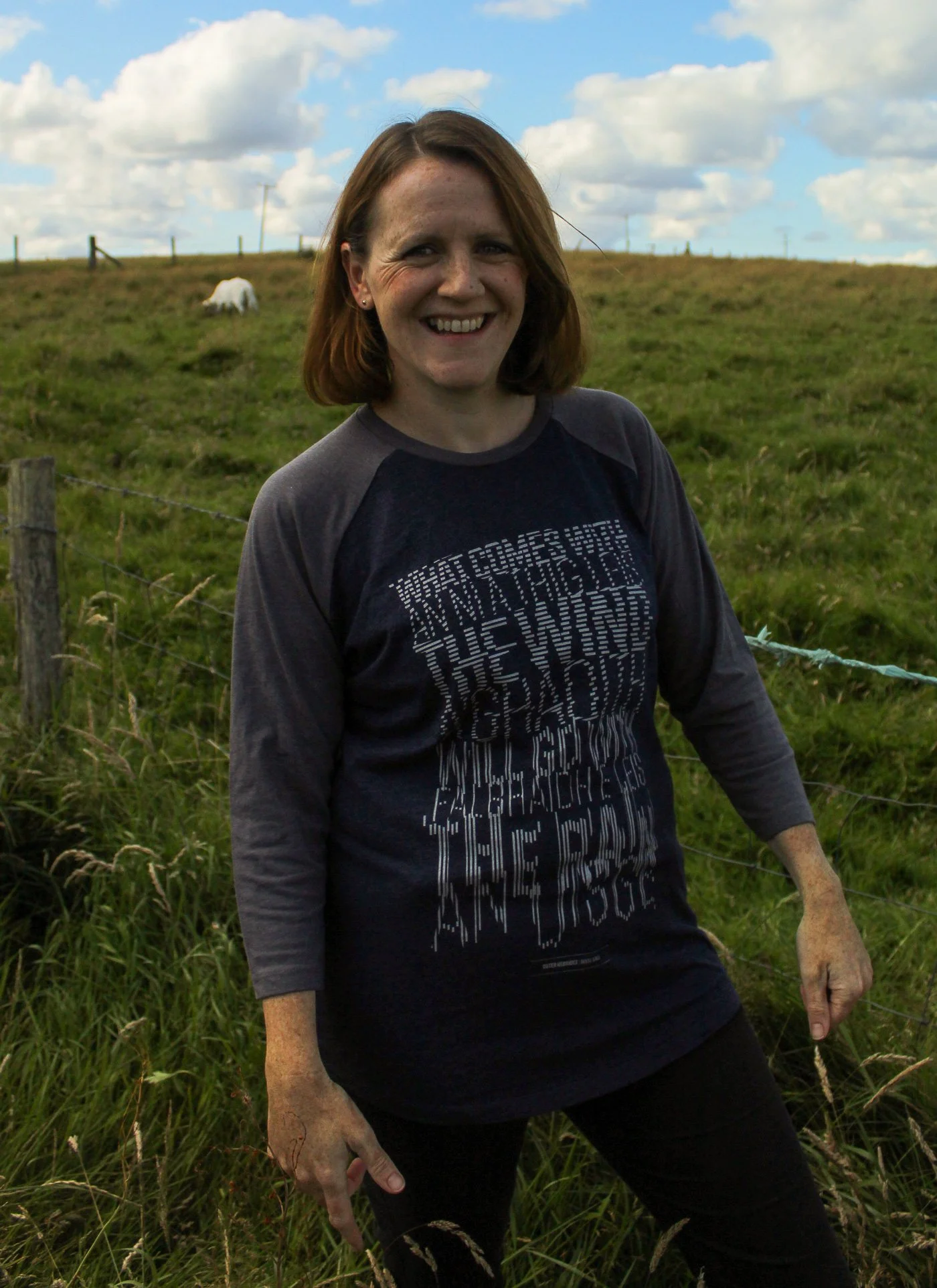 A woman in a field in the Outer Hebrides wearing a graphic design t-shirt