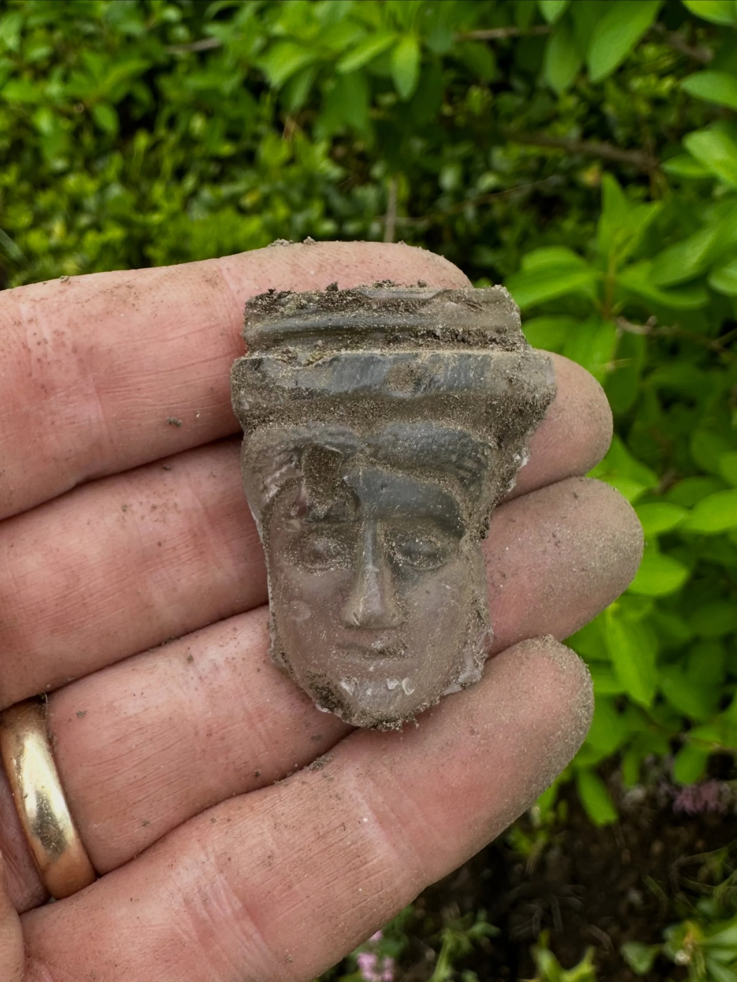 I was digging in the garden this morning and out from the dirt popped this molded clear glass face. Pretty cool! I wonder what this fragment once was. 🤔