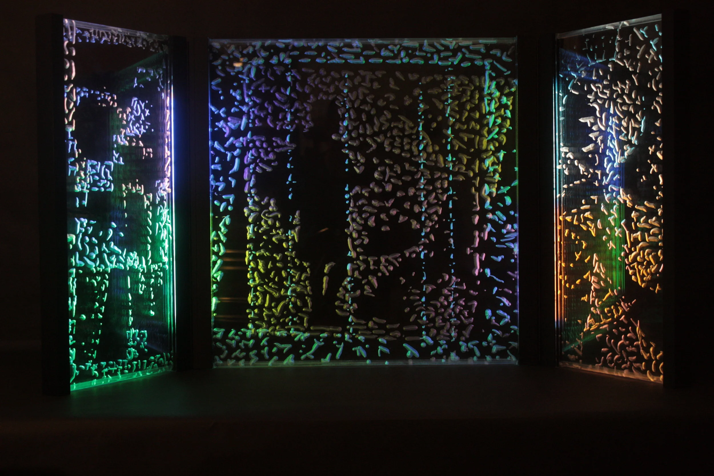  Westward Expansion, 2013. An illuminated triptych of hinged acrylic panels, etched with imagery based on events in California since the coming of Europeans. Lit with various colors of neon tubing, the clear acrylic panels are layered to create an ov
