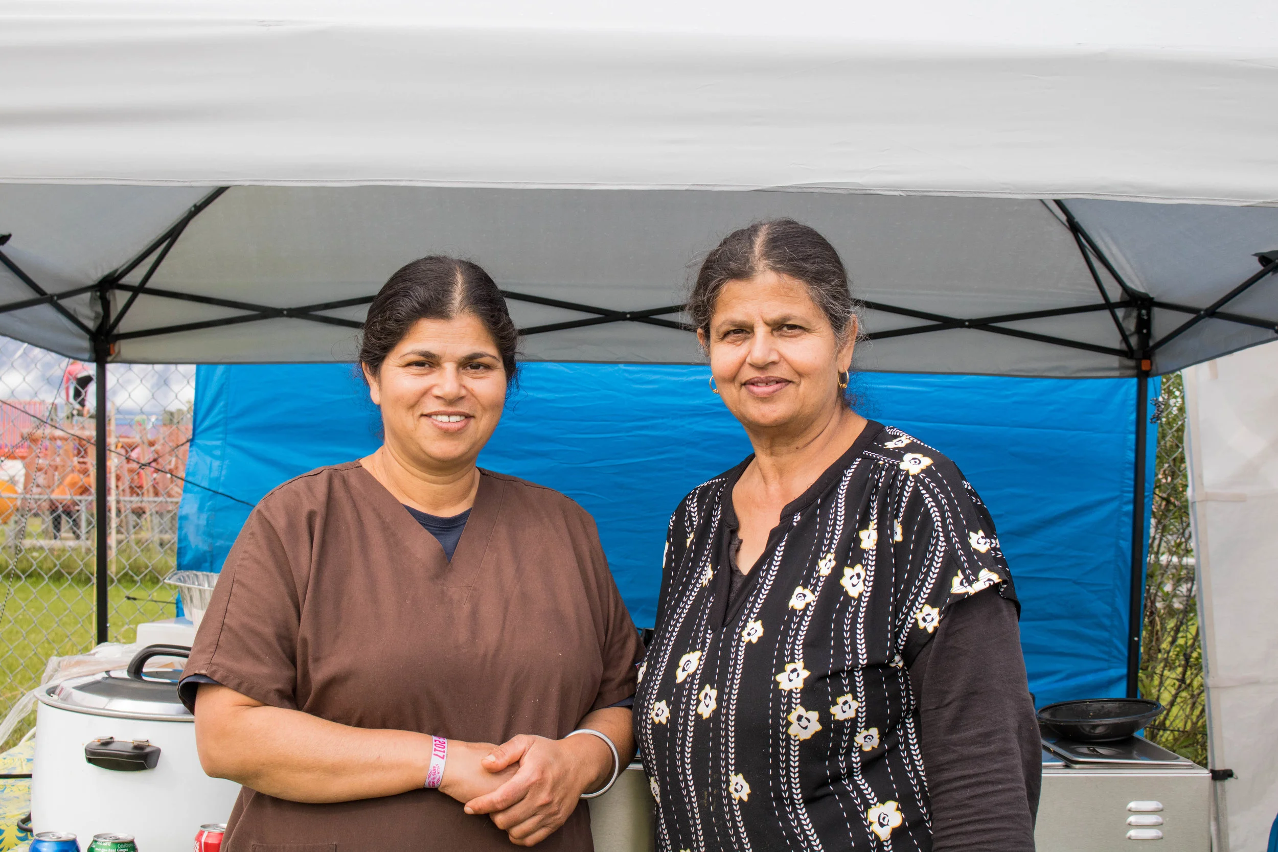Vicky Dhillon and her friend Sweety Sidhu standing outfront their food stand. 