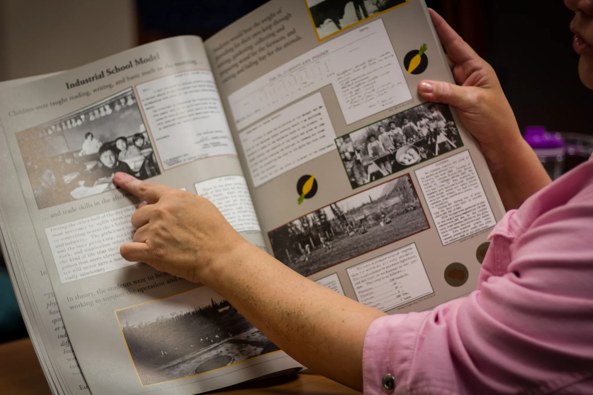 Isaac looks at a book on Residential Schools, using visual aids to show what life was like for these children.