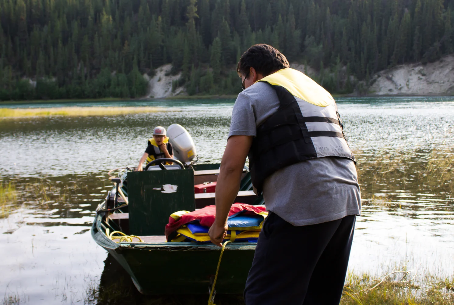 Charles Waugh pushes his family’s boat off the dock. They are going out onto the Yukon River to check their net for salmon. Photo by Kiera Kowalski