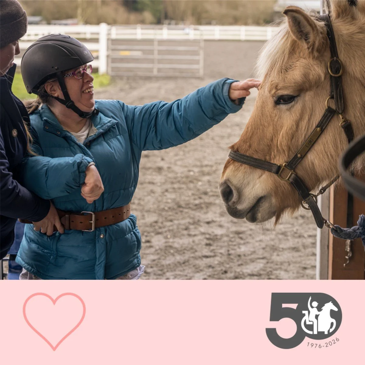 Participant reaches out to gently touch a horse’s face while being supported by a therapist.