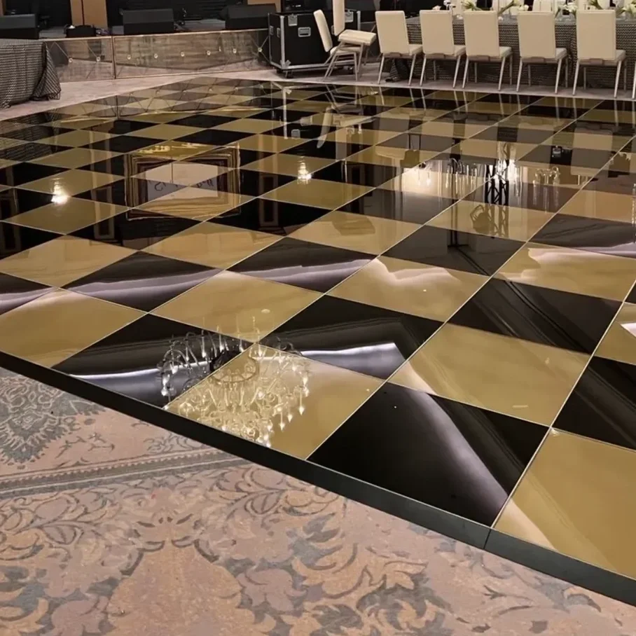 A shiny black and gold checkered dance floor next to a carpeted area with chairs and tables, possibly in a banquet hall or event space.