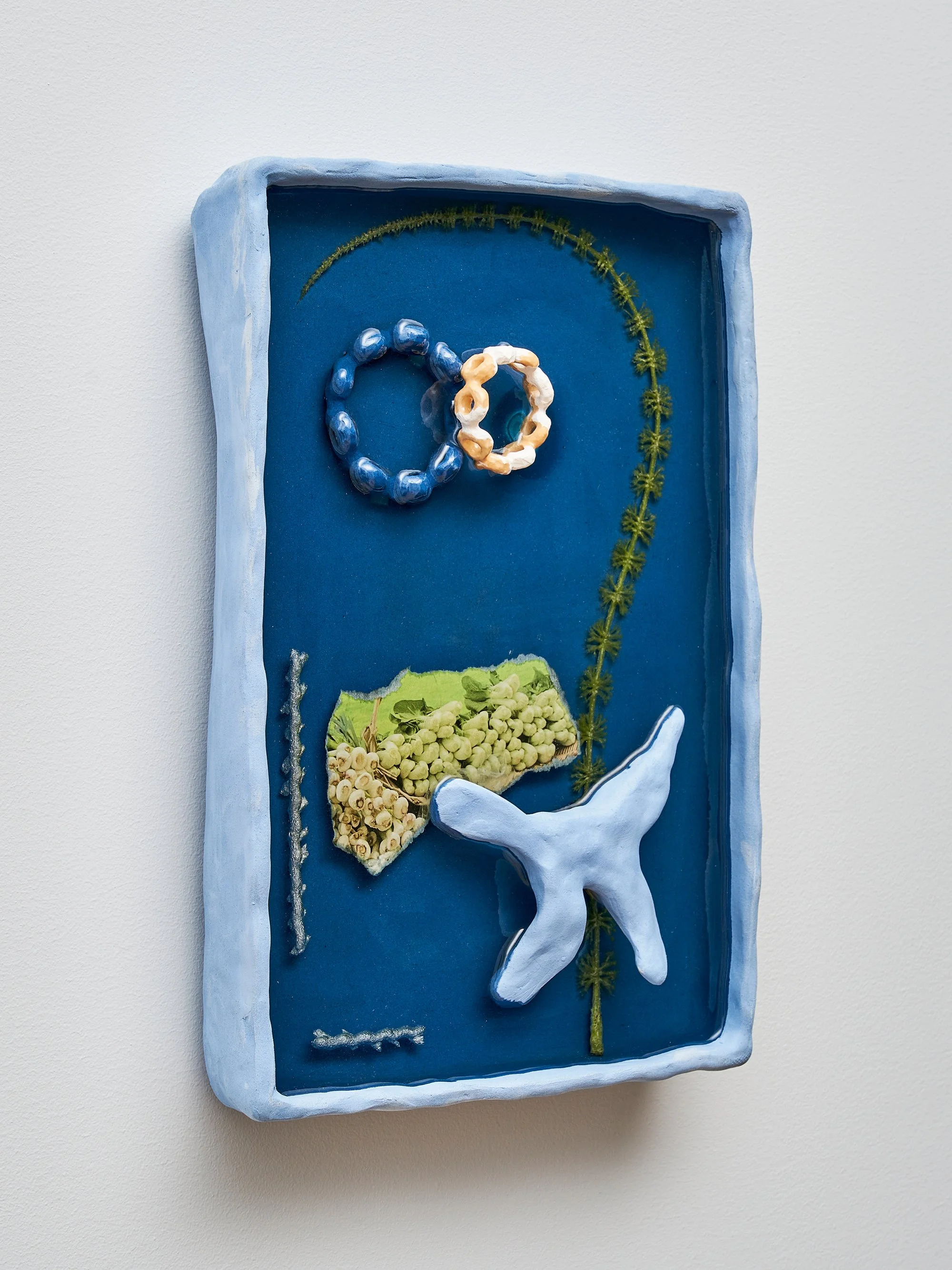   Yi Xin Tong,  Bok Choy , 2021, Bisque porcelain, blue clay bisqueware, resin, paper, plastic, pigment, 8 1/2 x 12 x 2 inches. Photo credit: Kunning Huang.  