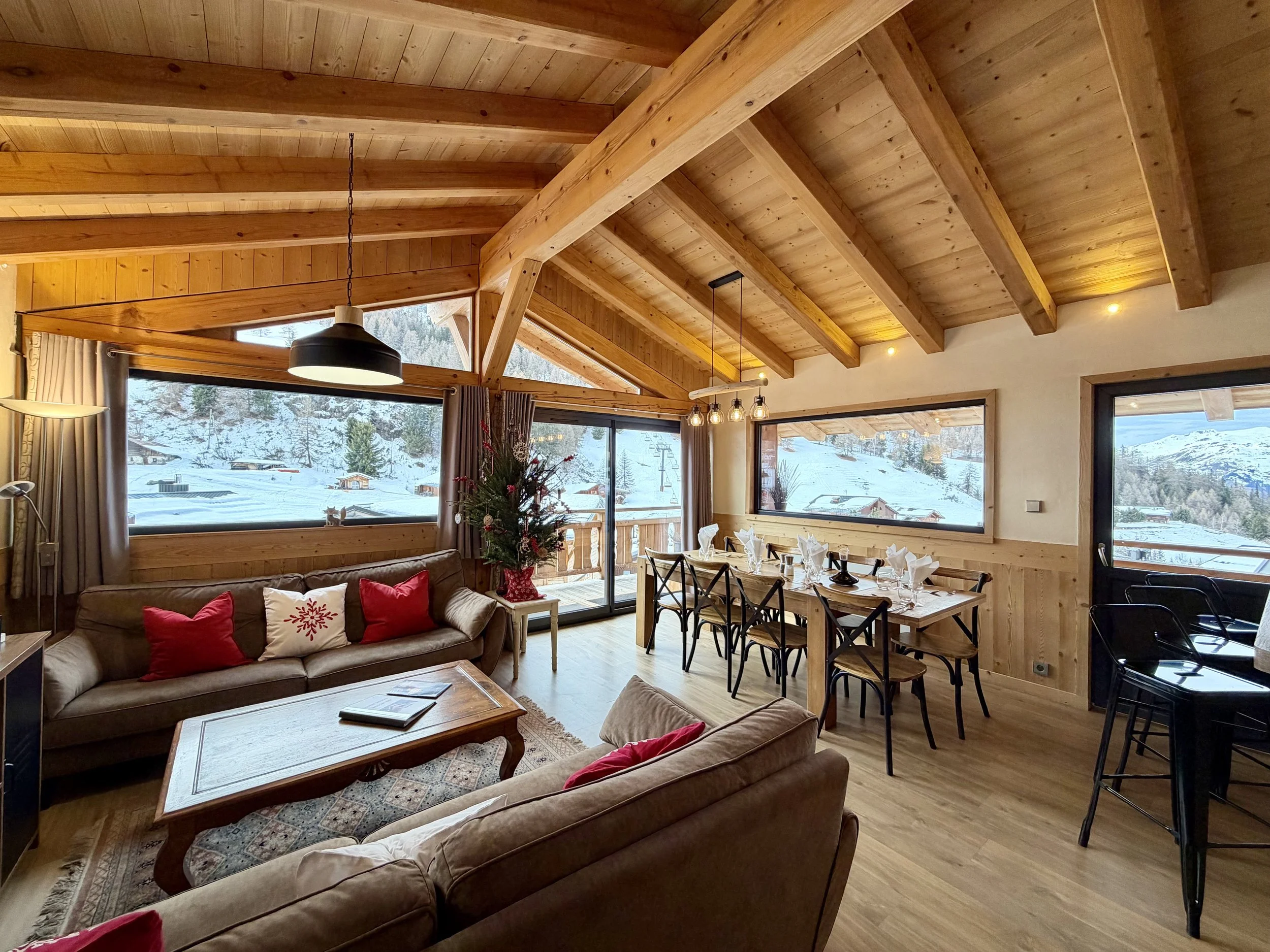 Alpine chalet living area with panoramic snowy views and a set dining table.