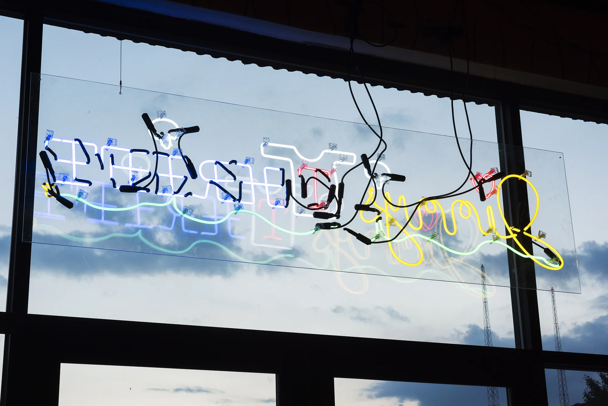 The "Jimmy's Thrift of New Davonhaime" neon sign, facing out from the exhibition to the parking lot at the Knockdown Center. Photo courtesy of the artist. 