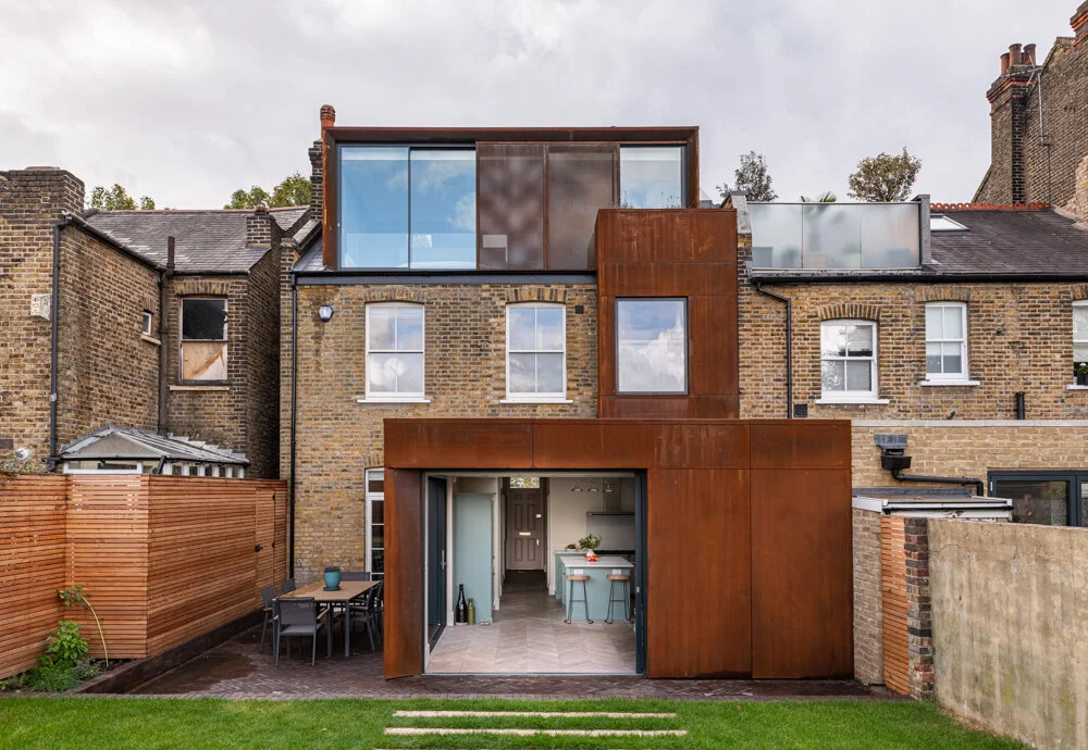 Corten steel rear and loft extension on a Victorian house in East Dulwich, its roofline set above the original brick