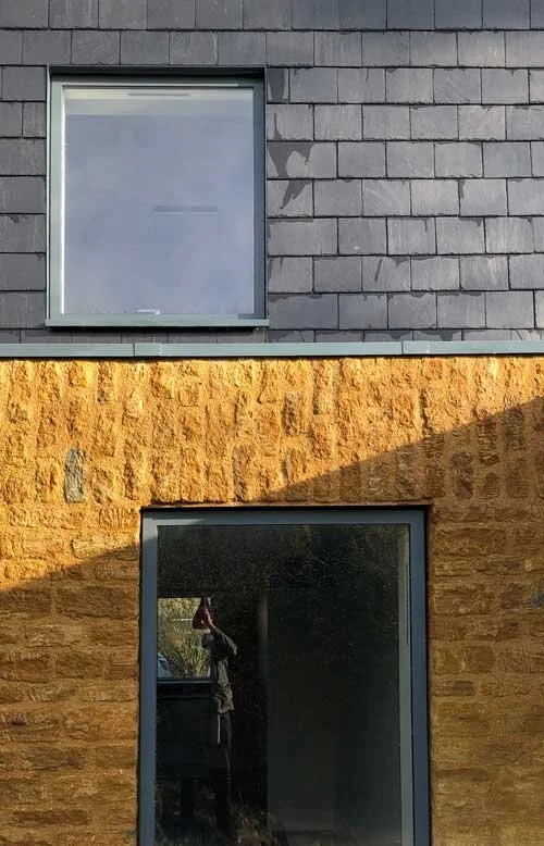 Natural slate hanging wall over hamstone wall with aluminium framed windows by Lendel Stephens Architects