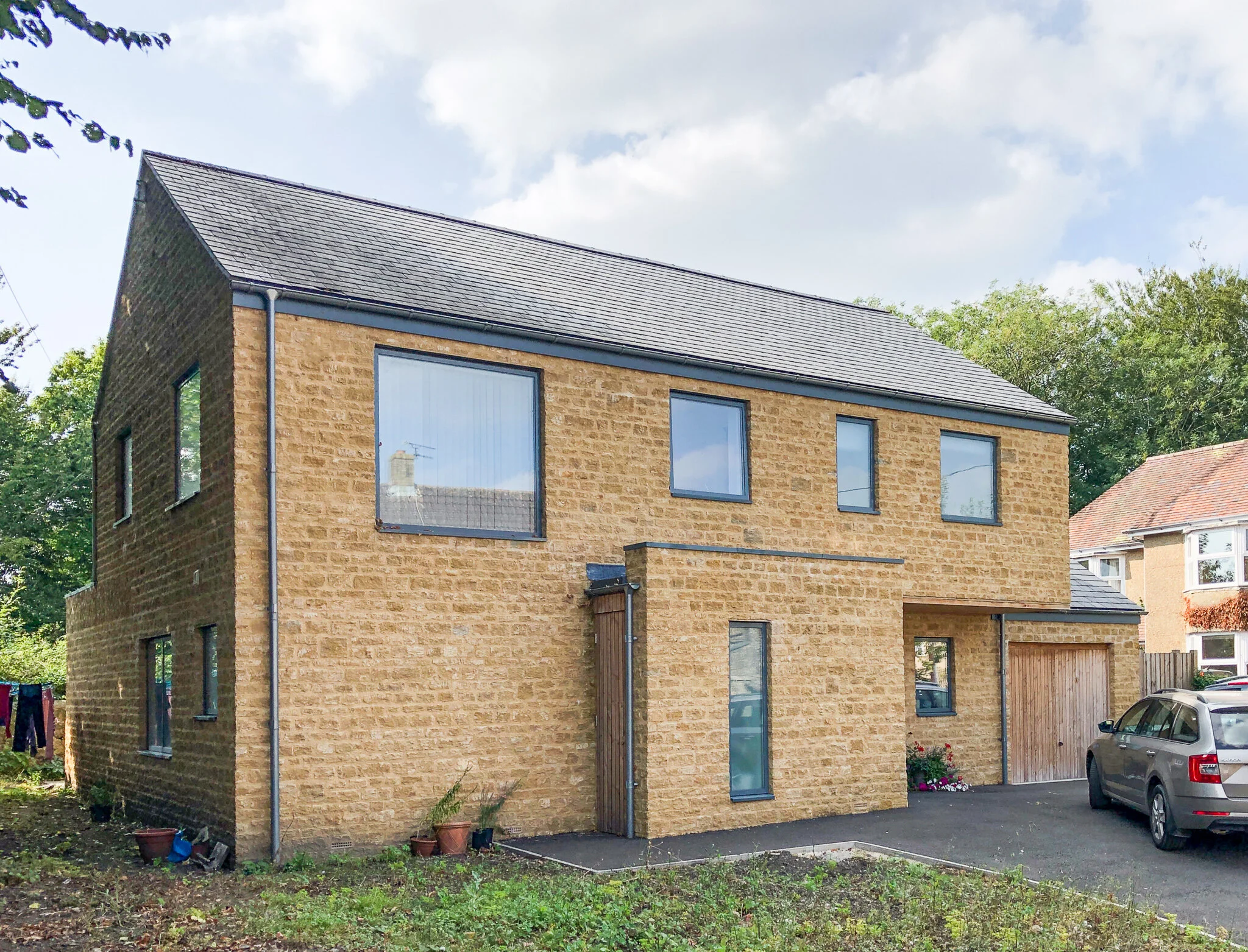 New house with large pushed windows in stone facade by Lendel Stephens Architects