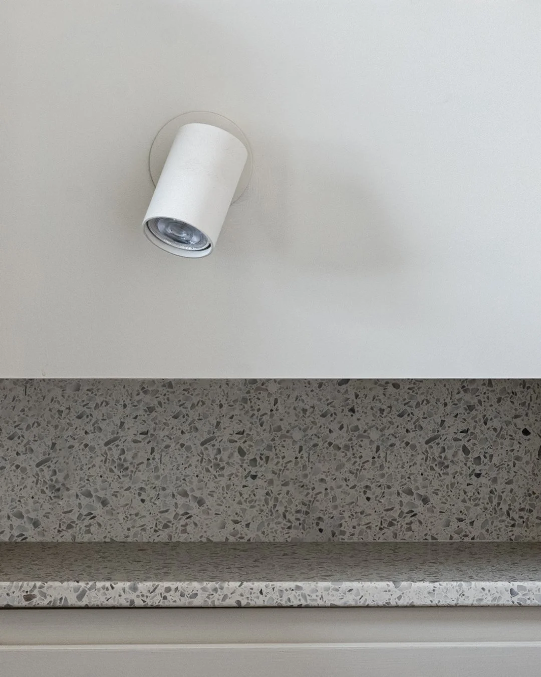 Terrazzo shelf built into a wall niche at Lordship Lane, lit by a wall-mounted spotlight.