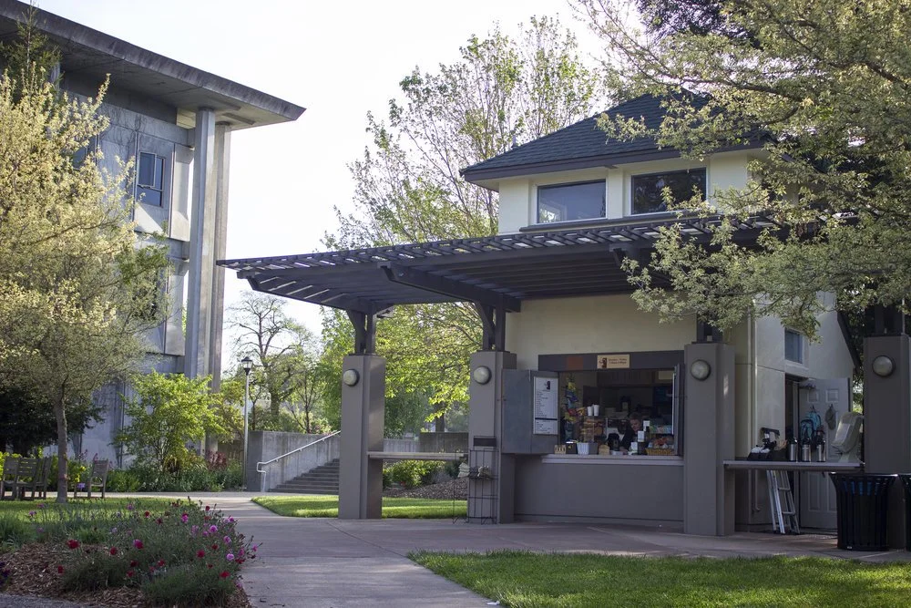 a small building surrounded by trees with a covered front porch and service window