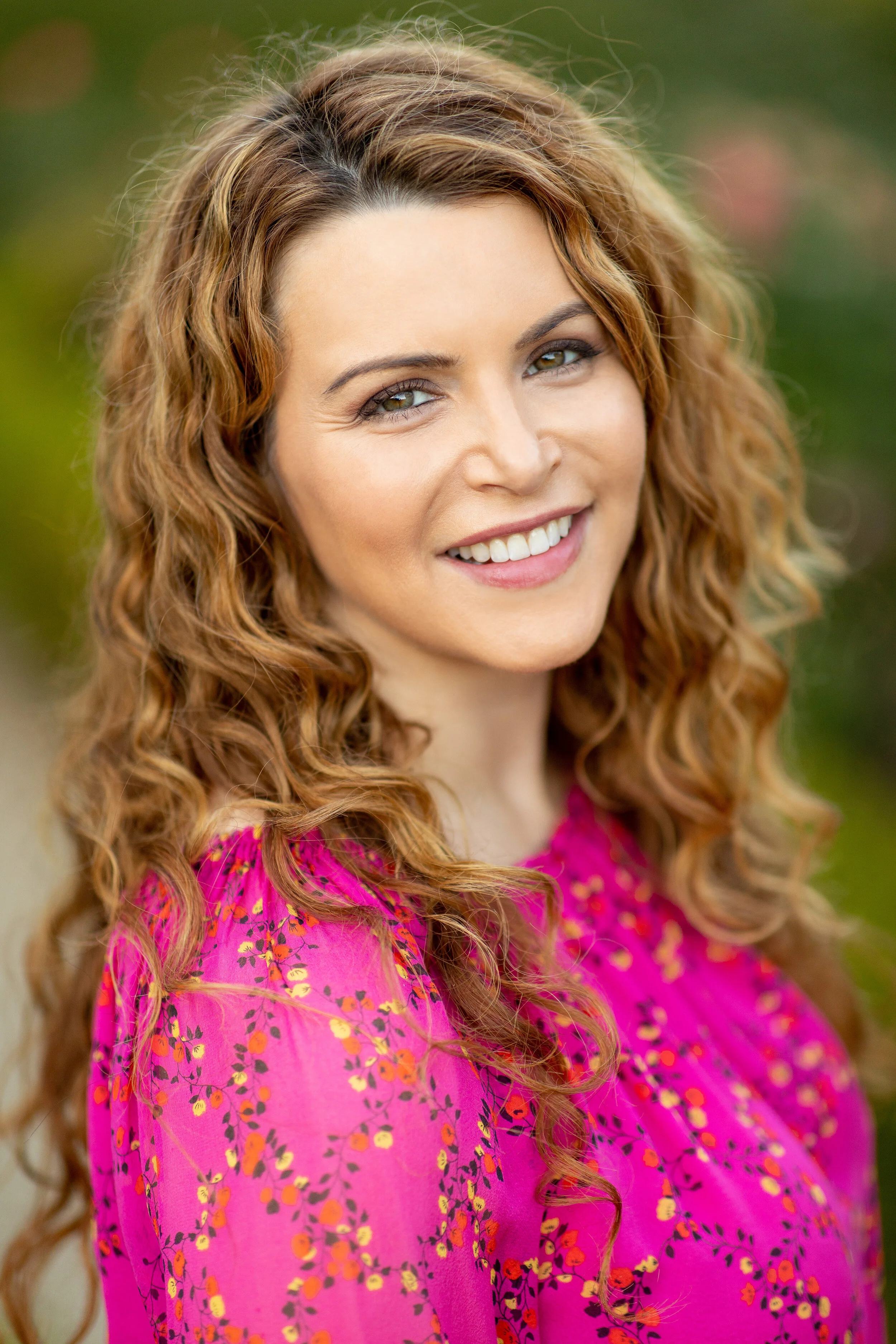 A photo of EMDR therapist Leslie Miranda in a bright pink floral shirt smiling a the camera.