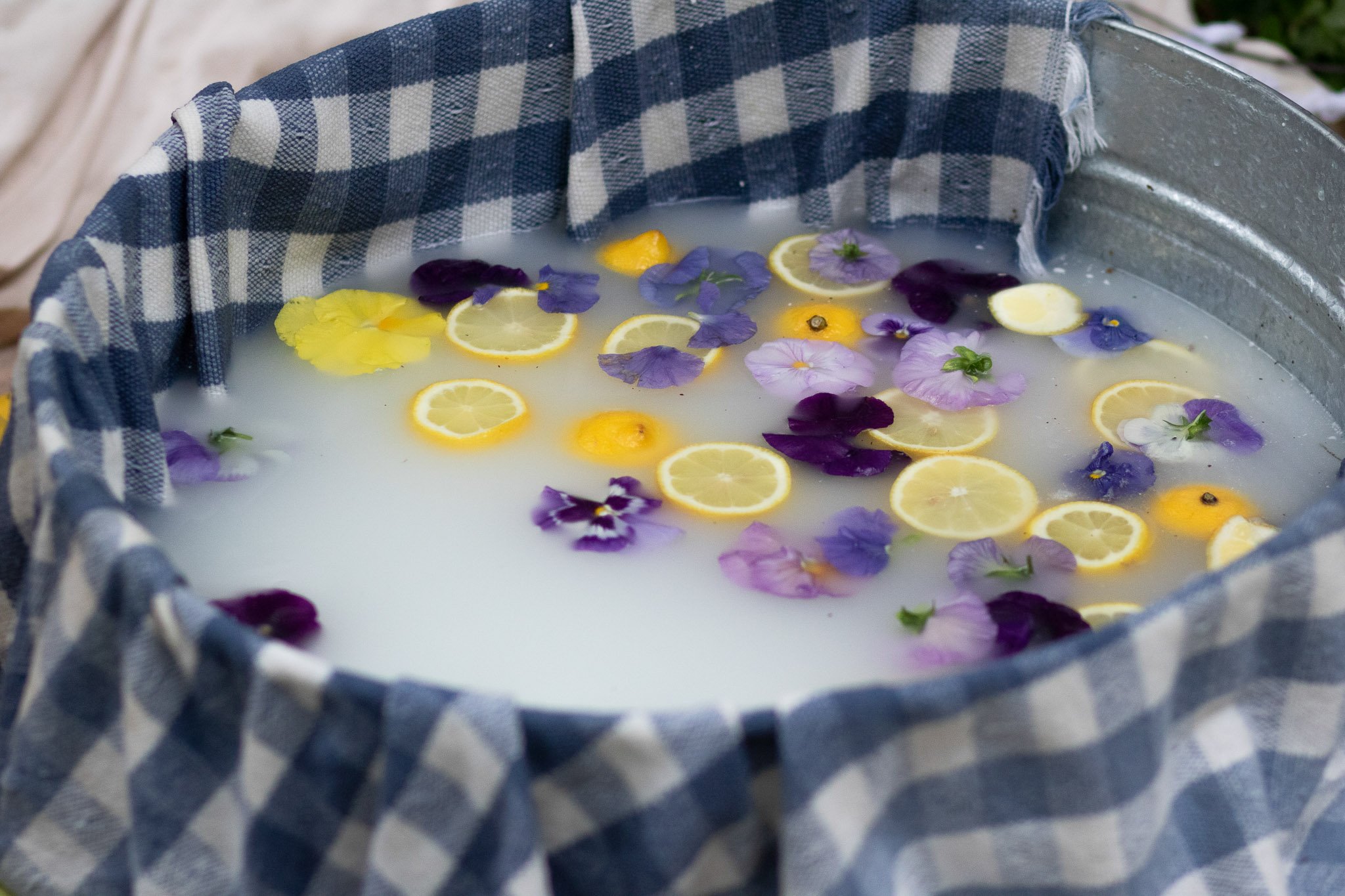 Lemon milk bath with floating lemon slices and purple edible flowers at a garden first birthday party.