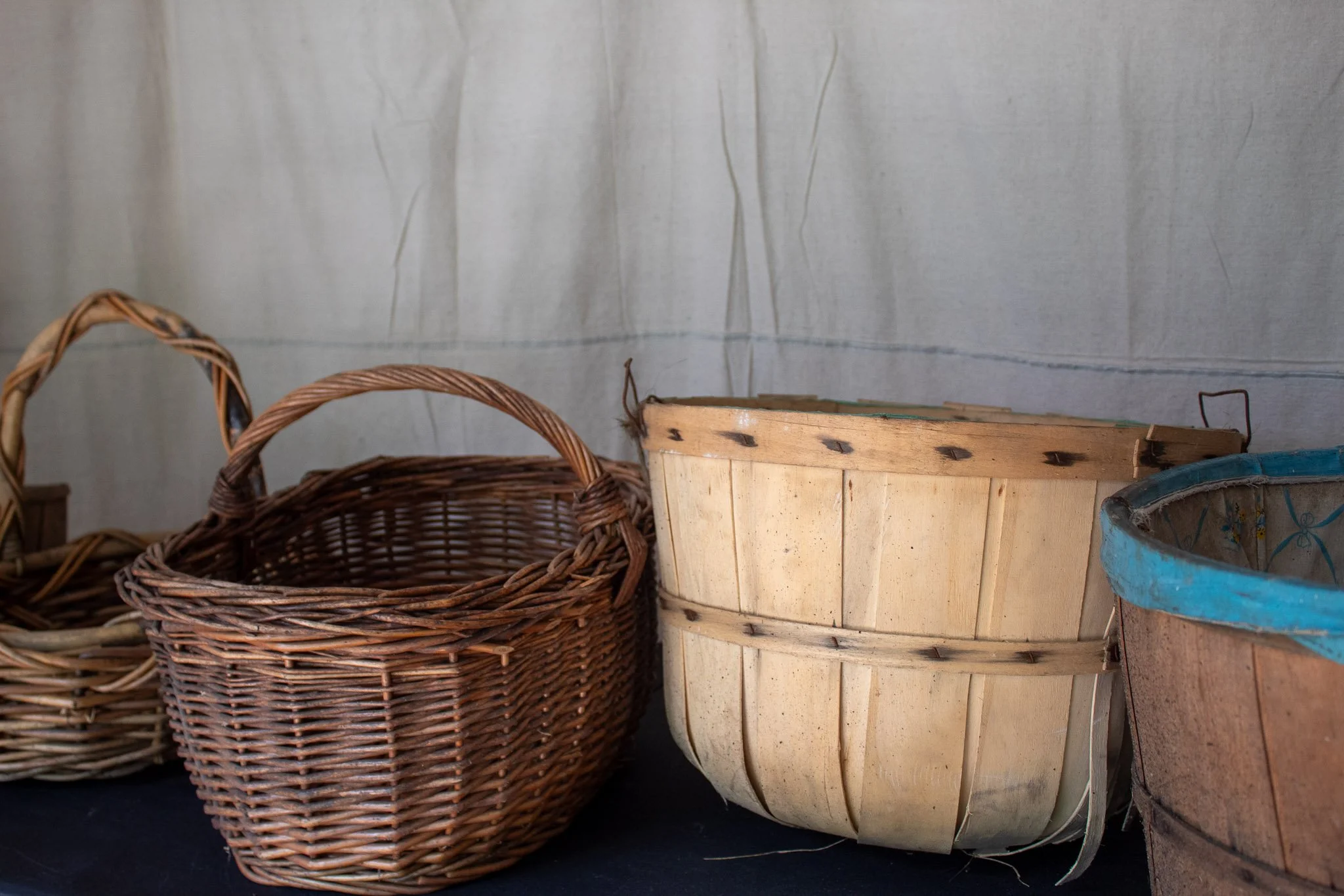 Assorted wicker and wooden baskets arranged against a canvas backdrop for a rustic garden party display.