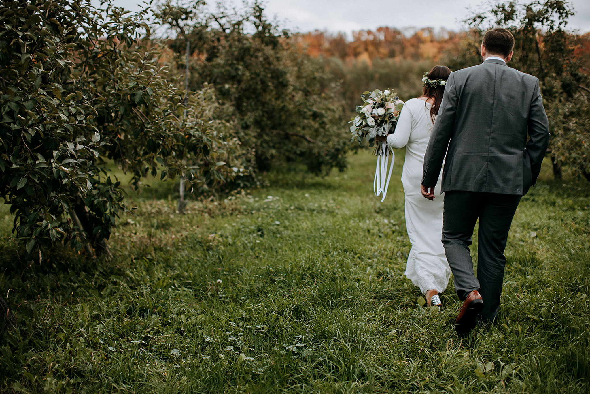 couple heading into apple orchard at meaford barn wedding