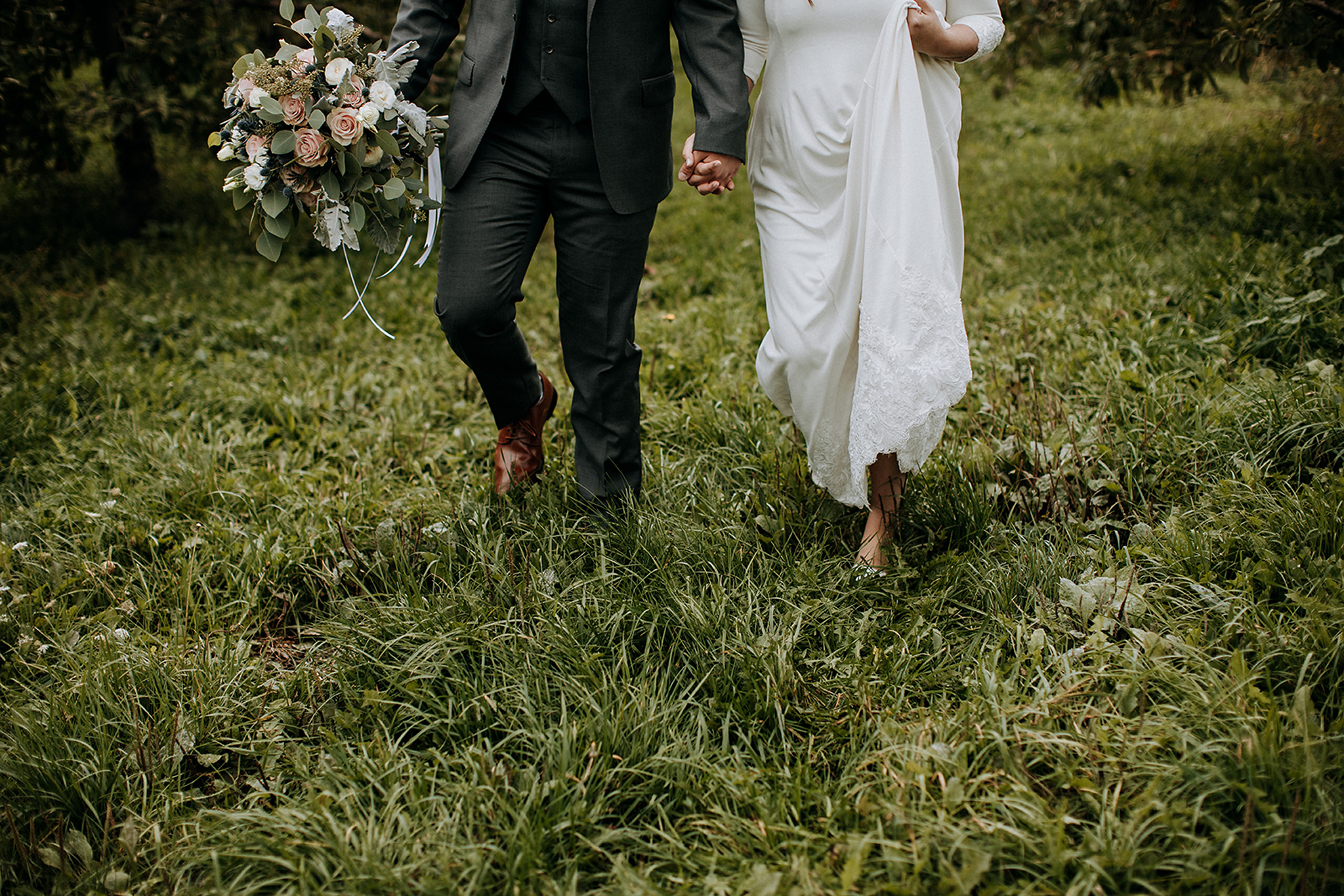 couple walking through apple orchard at meaford barn wedding