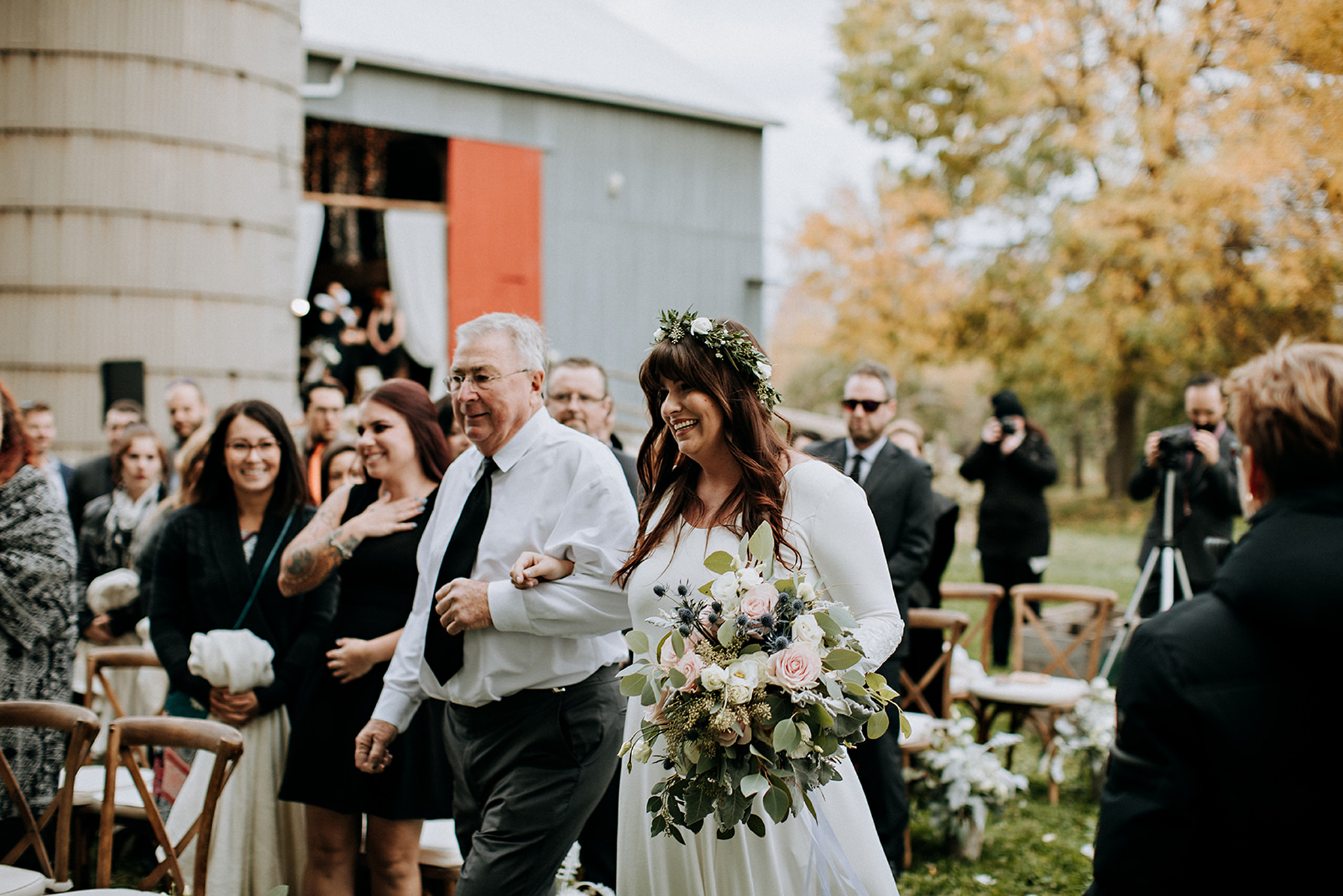 bride walks down the aisle with her dad at meaford barn wedding