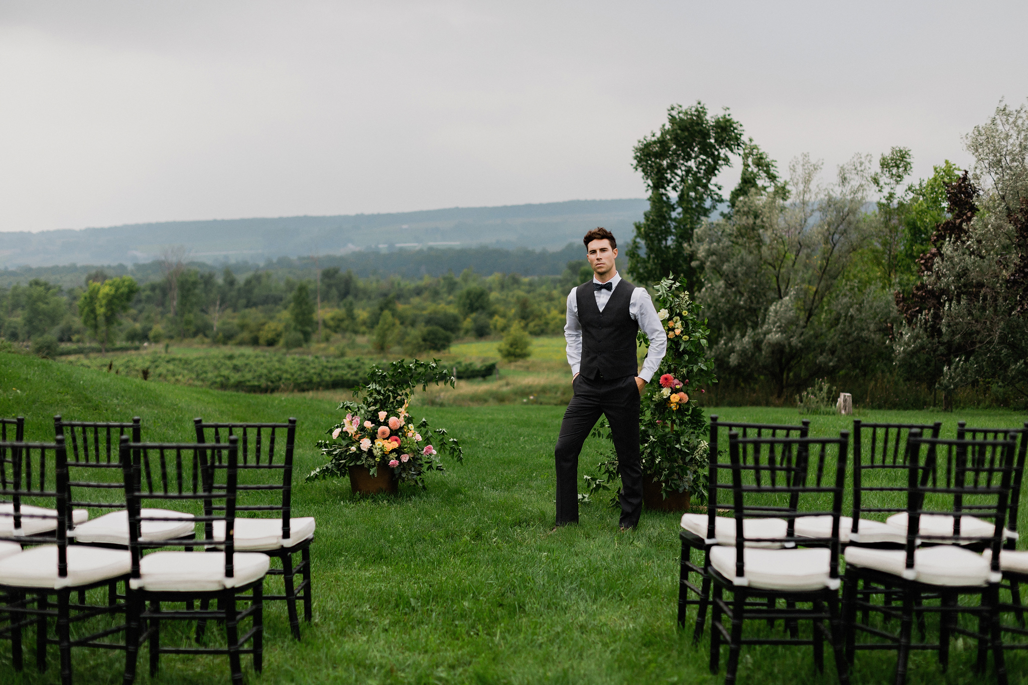 Groom looking dapper in a vest and slacks with sweeping landscap
