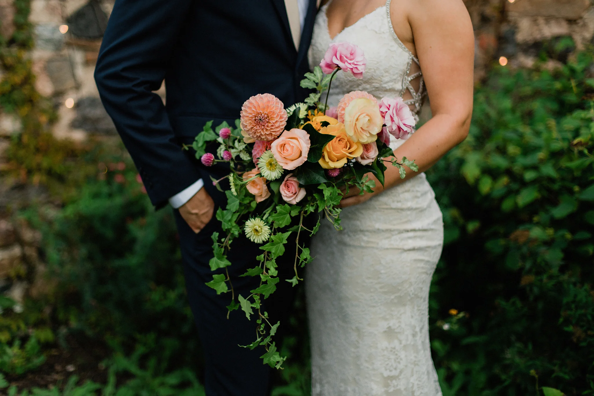 A sunset coral toned bridal bouquet with trailing ivy