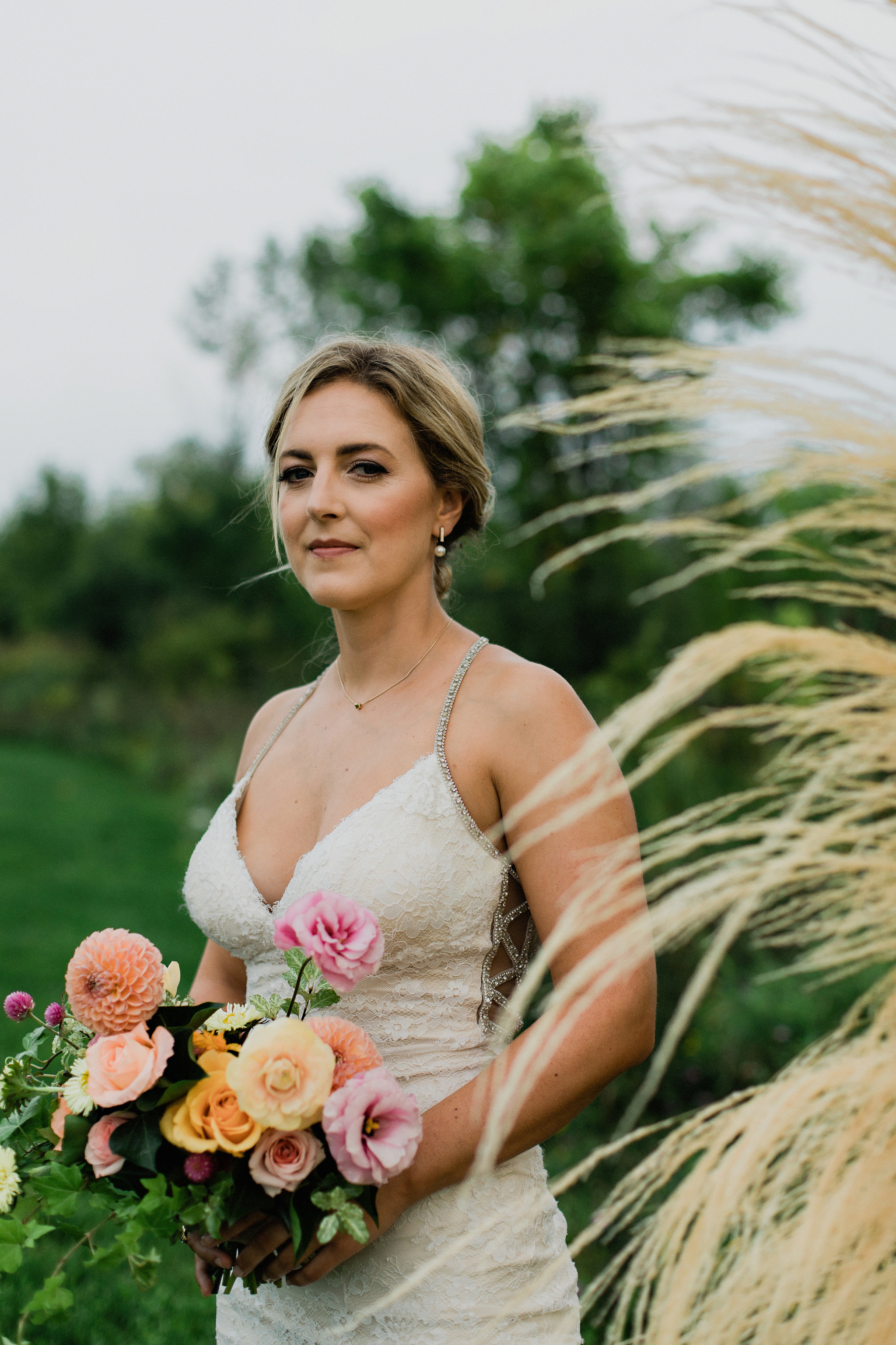 Beautiful bridal portrait with dried grasses and coral toned bou