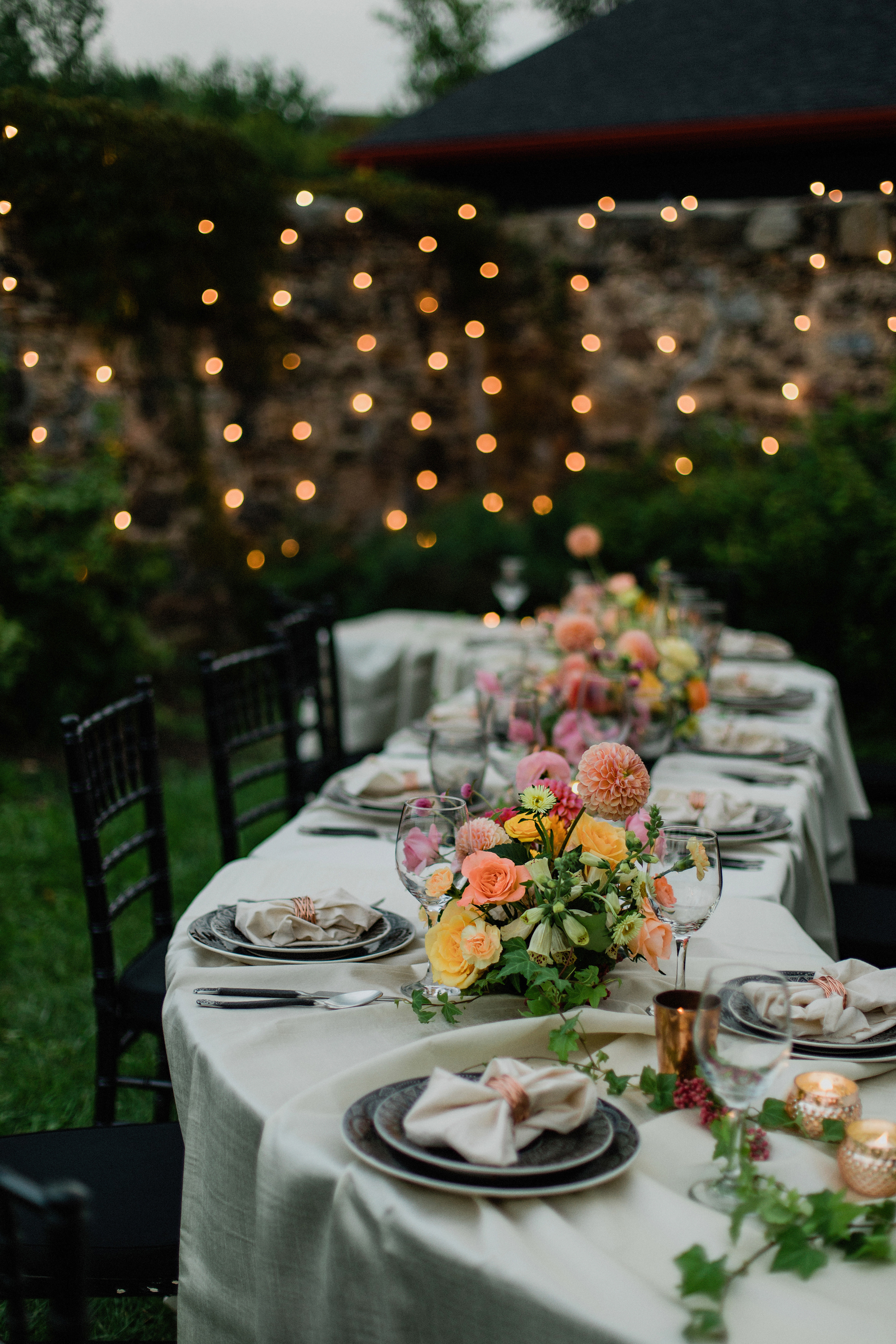 outdoor S curve wedding table with coral toned floral centrepiec