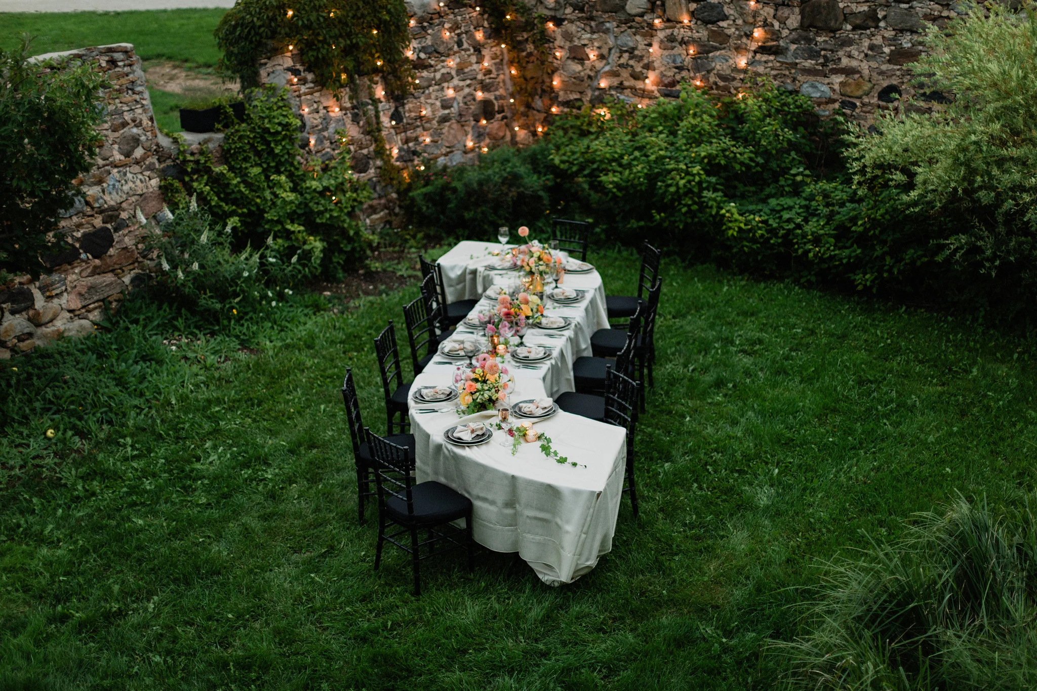outdoor S curve wedding table with coral toned floral centrepiec