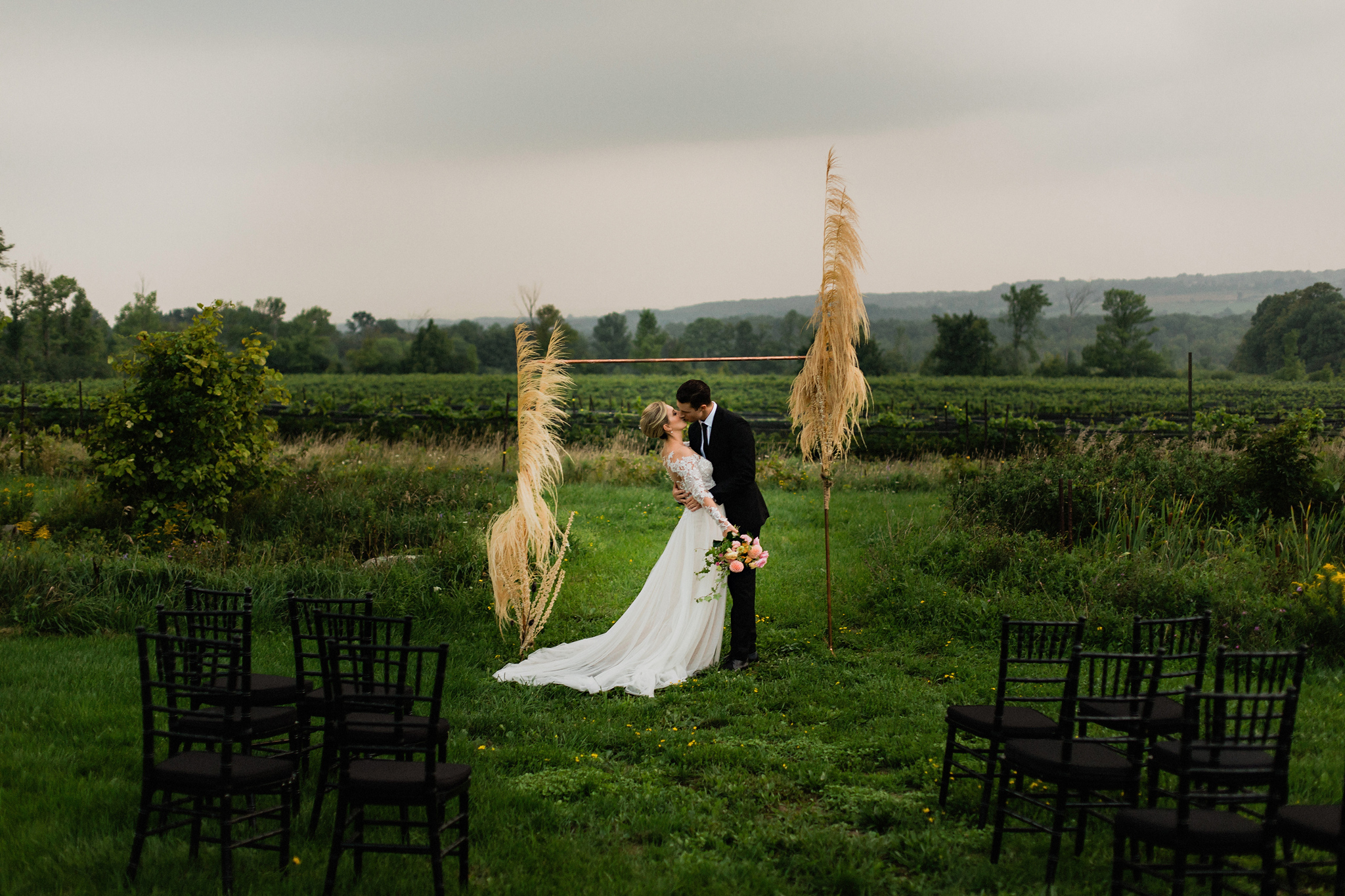 First kiss under copper and dried grasses arch at Coffin Ridge B