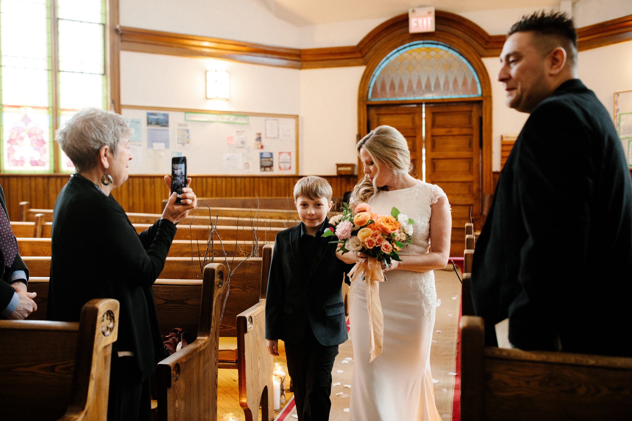 Bride and son walk down aisle with coral bouquet at intimate Tho