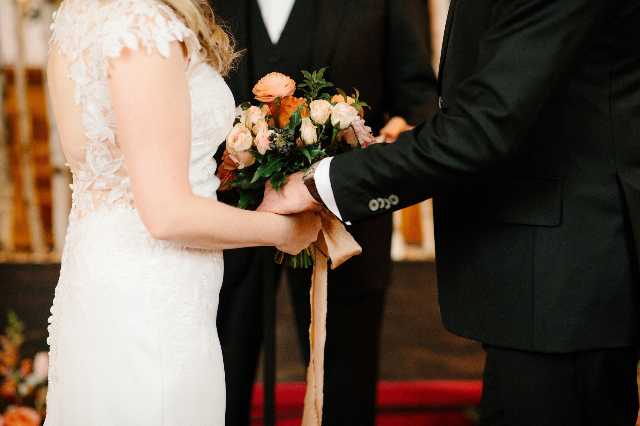 Couple holding hands with coral bridal bouquet in Thornbury chur