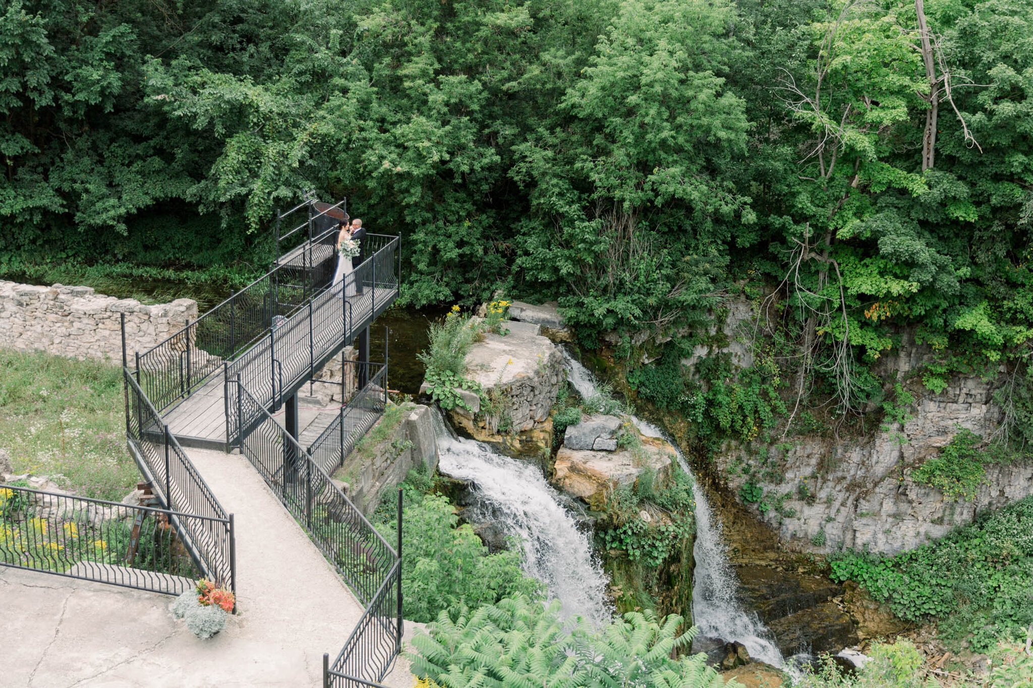 Couple standing on bridge over water fall at Walters Falls Inn a