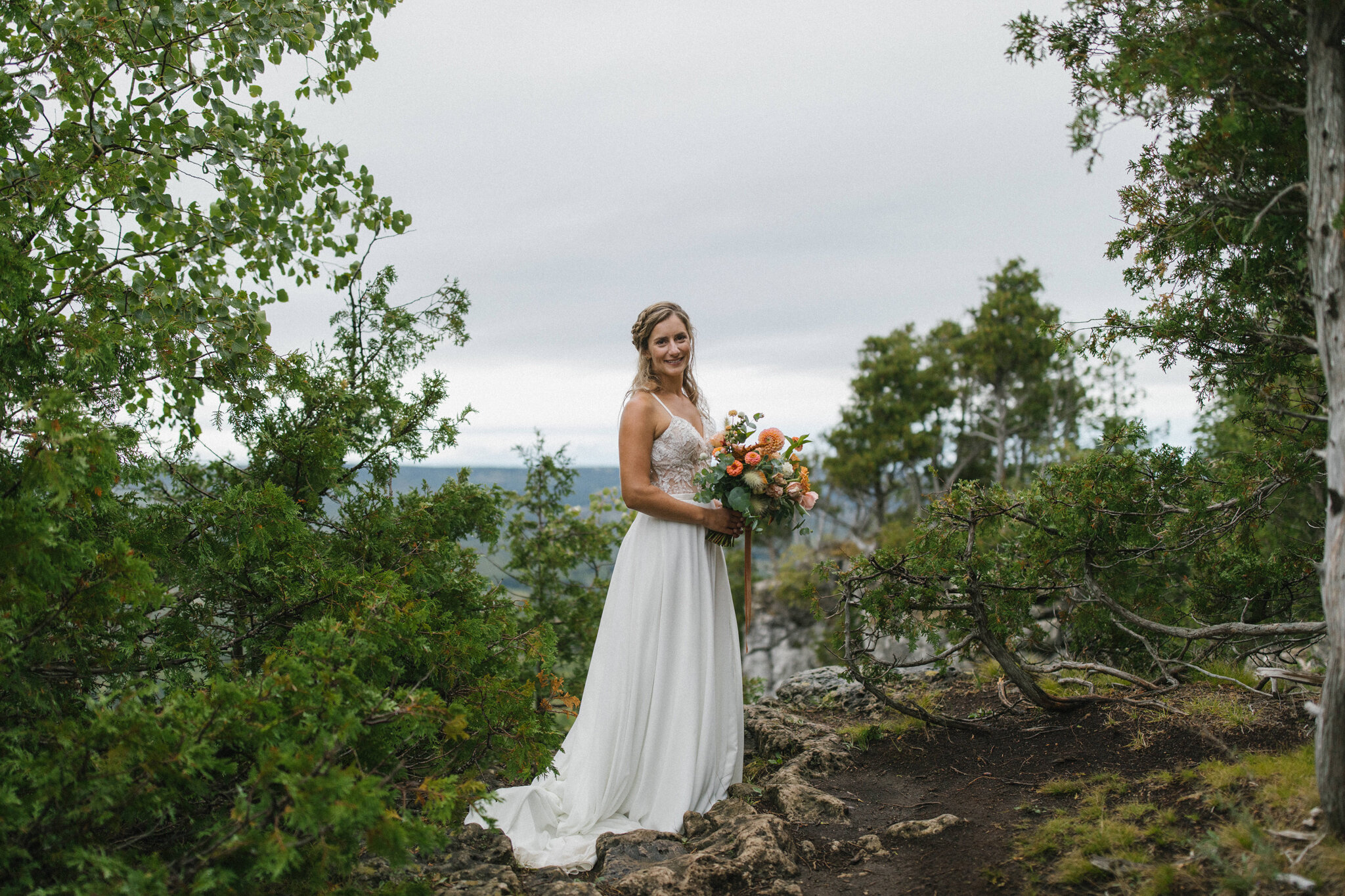 camera aware portrait of bride on top of old baldy with bouquet