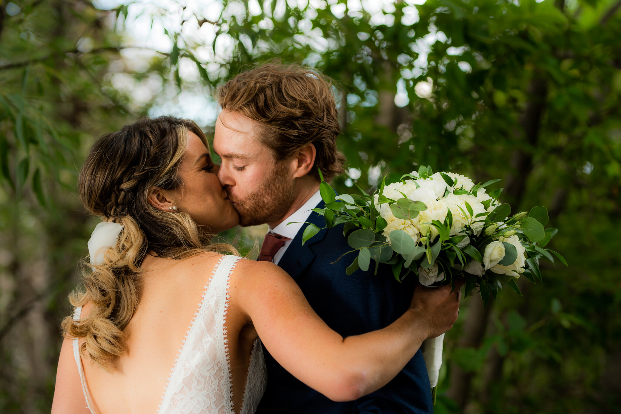 bride and groom kiss in forest by jessica crandlemire