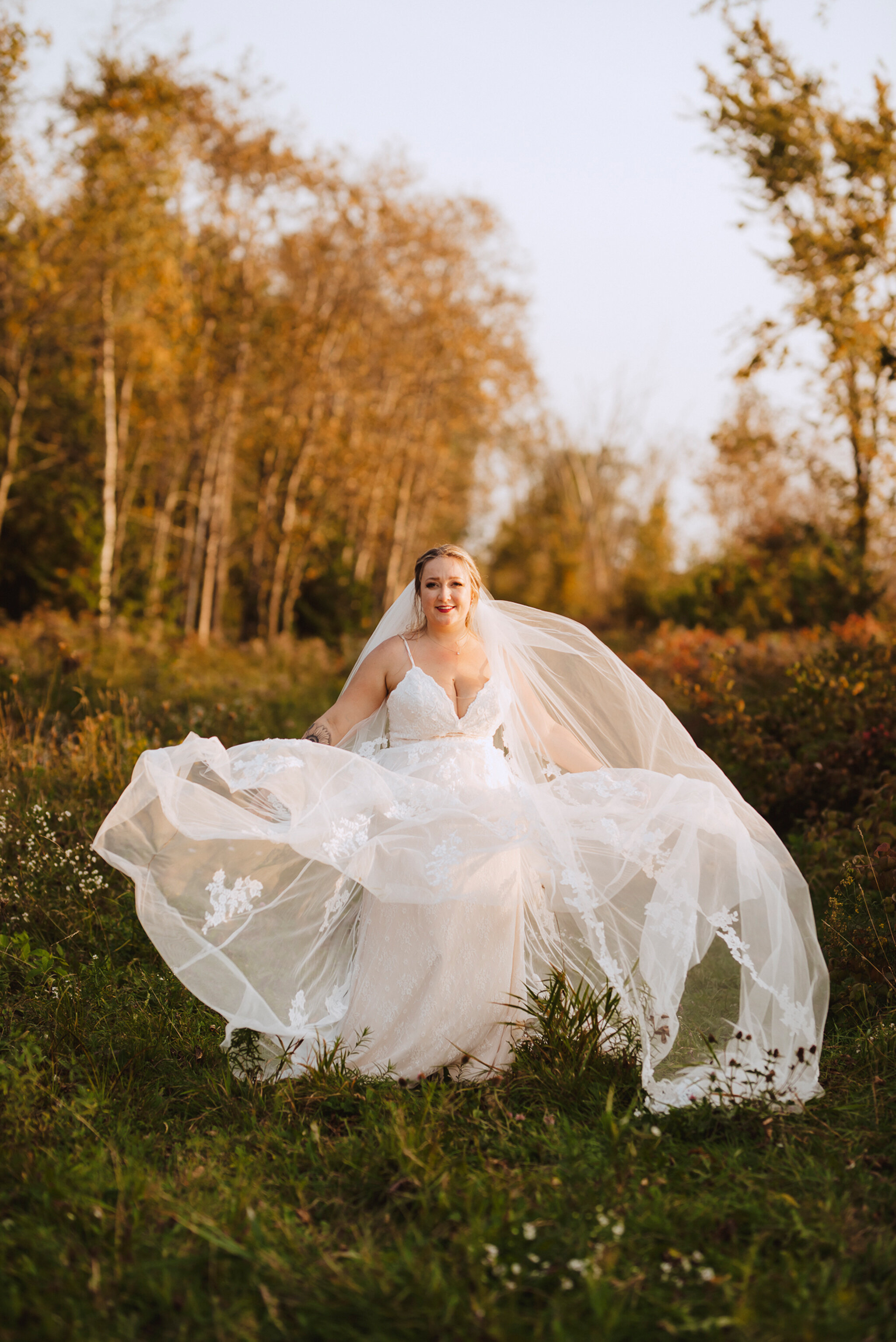 beautiful bride twirls lace gown in fall field by jessica crandl