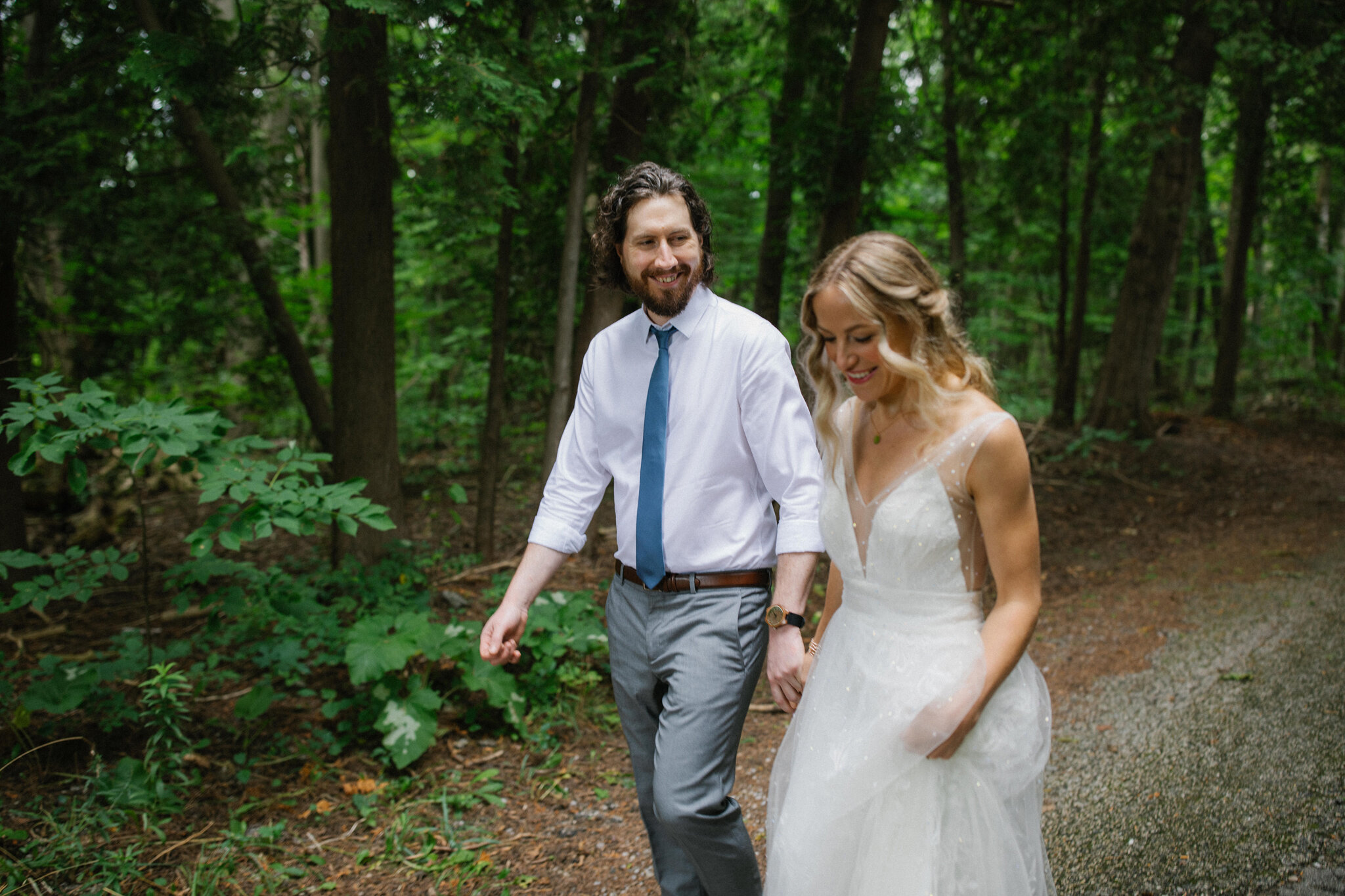 Groom stares at bride walking forest Meaford