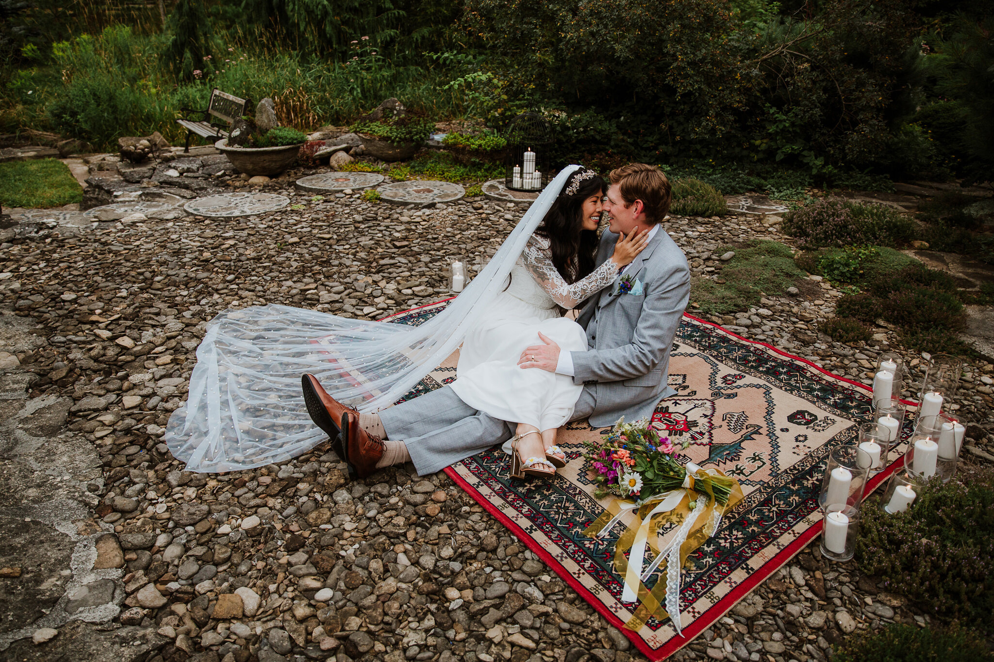 couple snuggling on vintage rug with wedding dress and veil