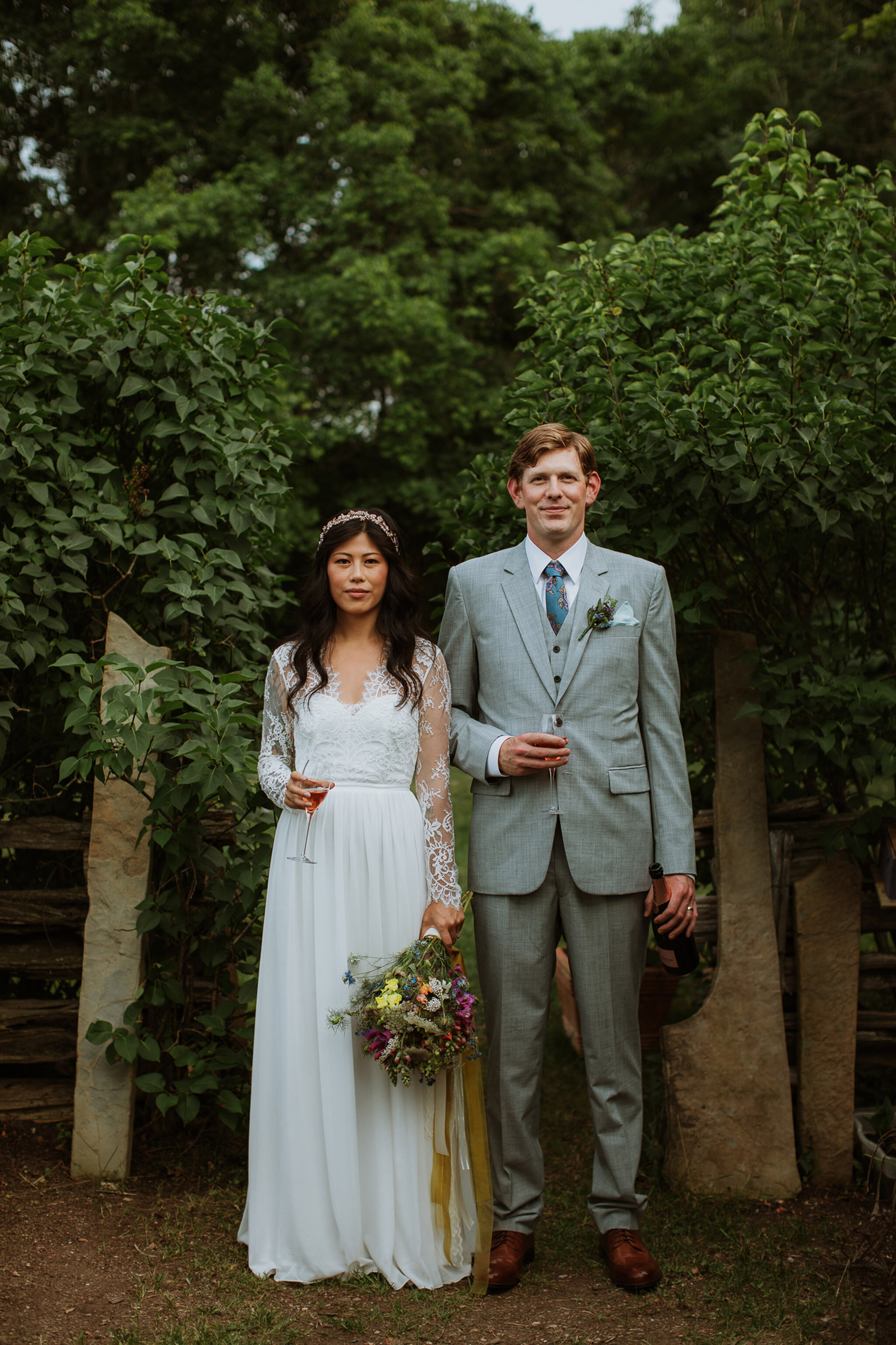 wedding couple with grey suit and lace dress holding champagne