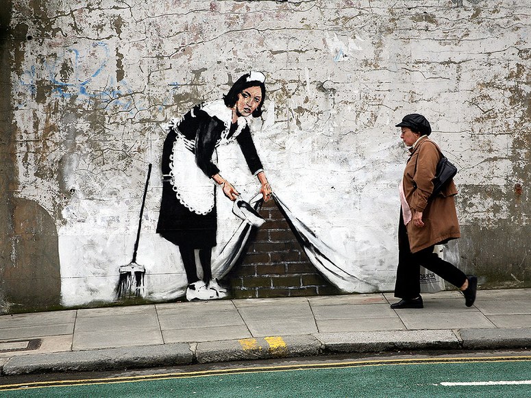 Banksy (2006) Sweeping it Under the Carpet. Stencil graffiti on a wall in London. 