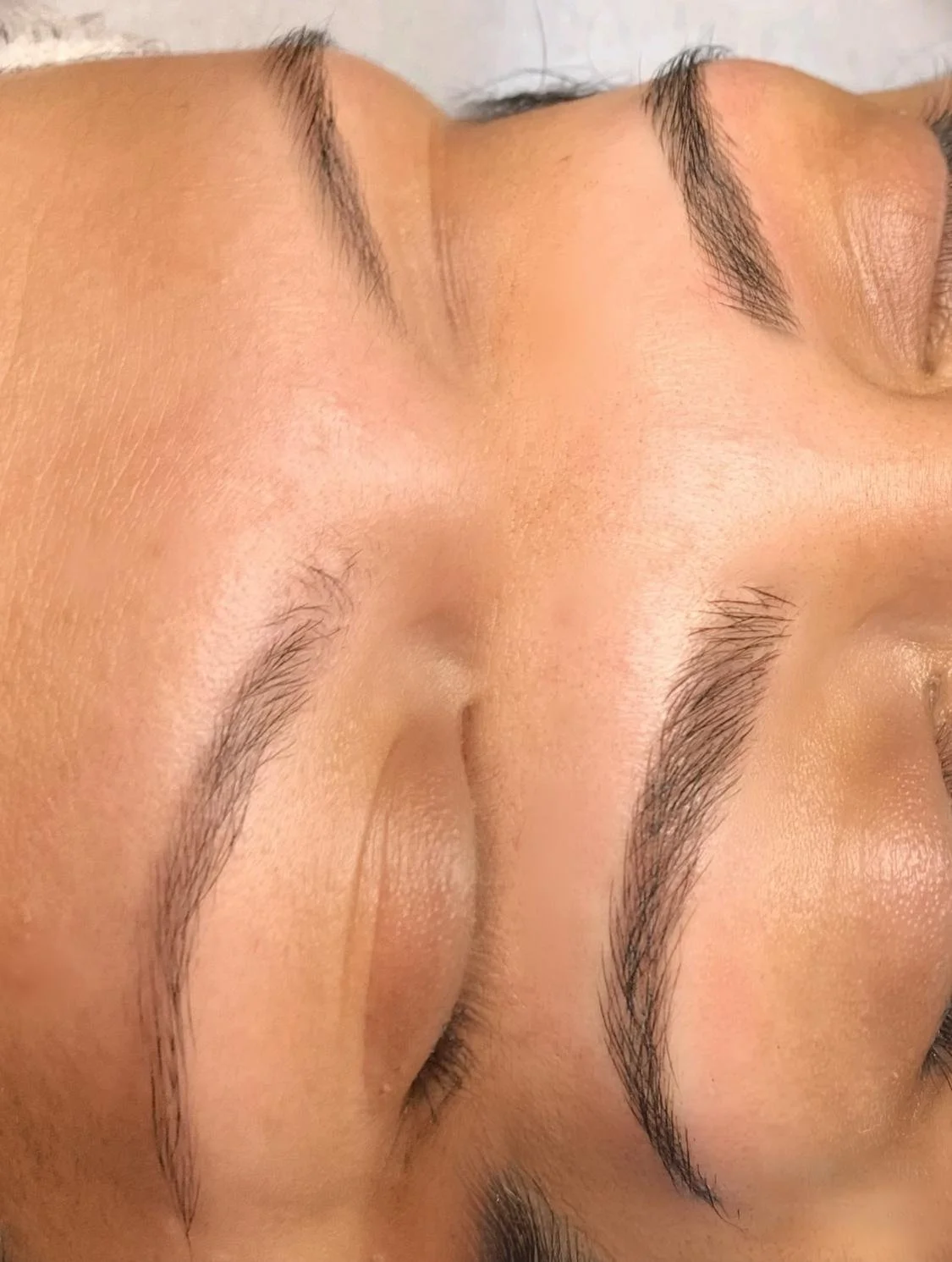 Close-up of a person's well-groomed eyebrows with closed eyes, showcasing eyebrow shaping.