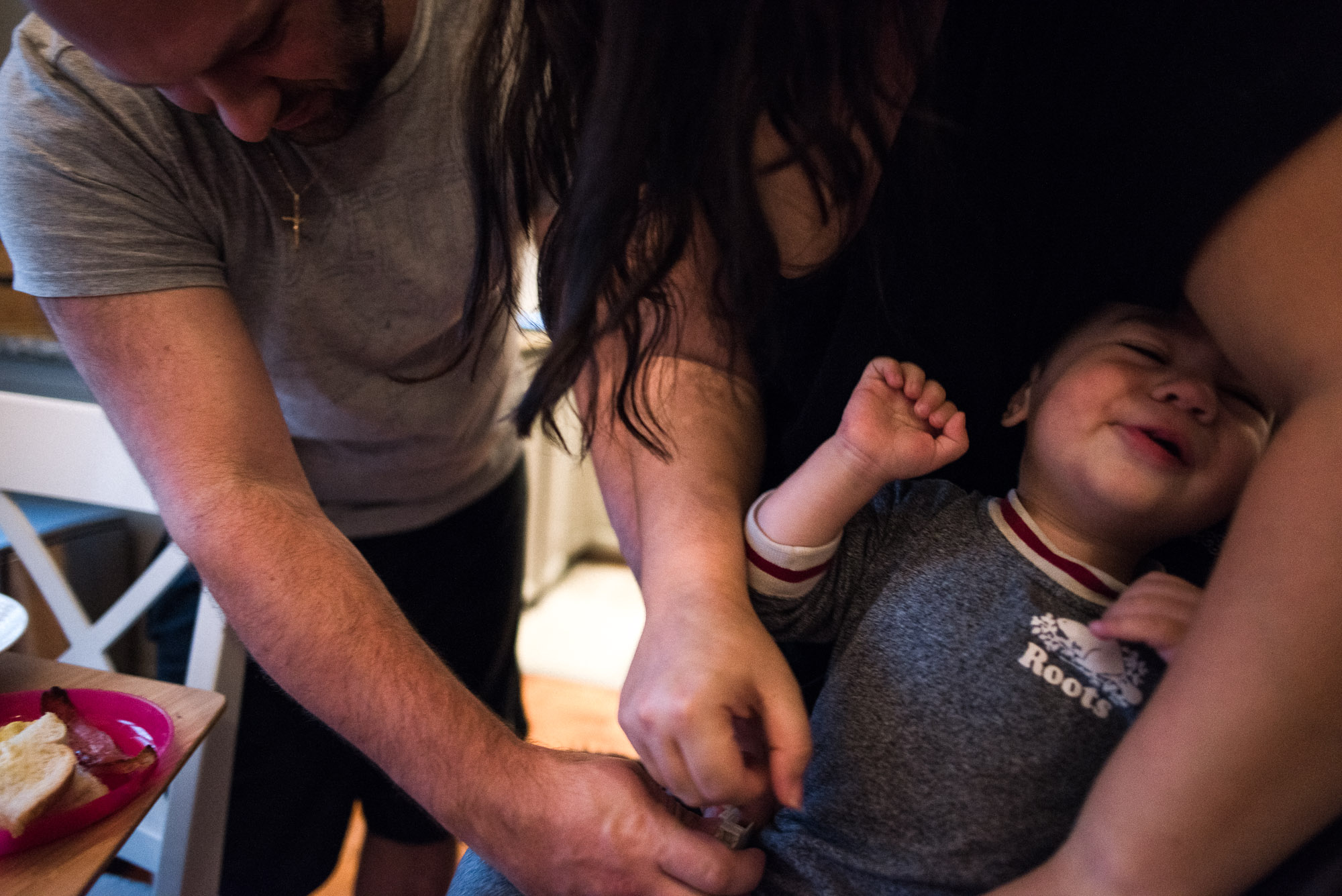 mom and dad try to strap toddler into high chair
