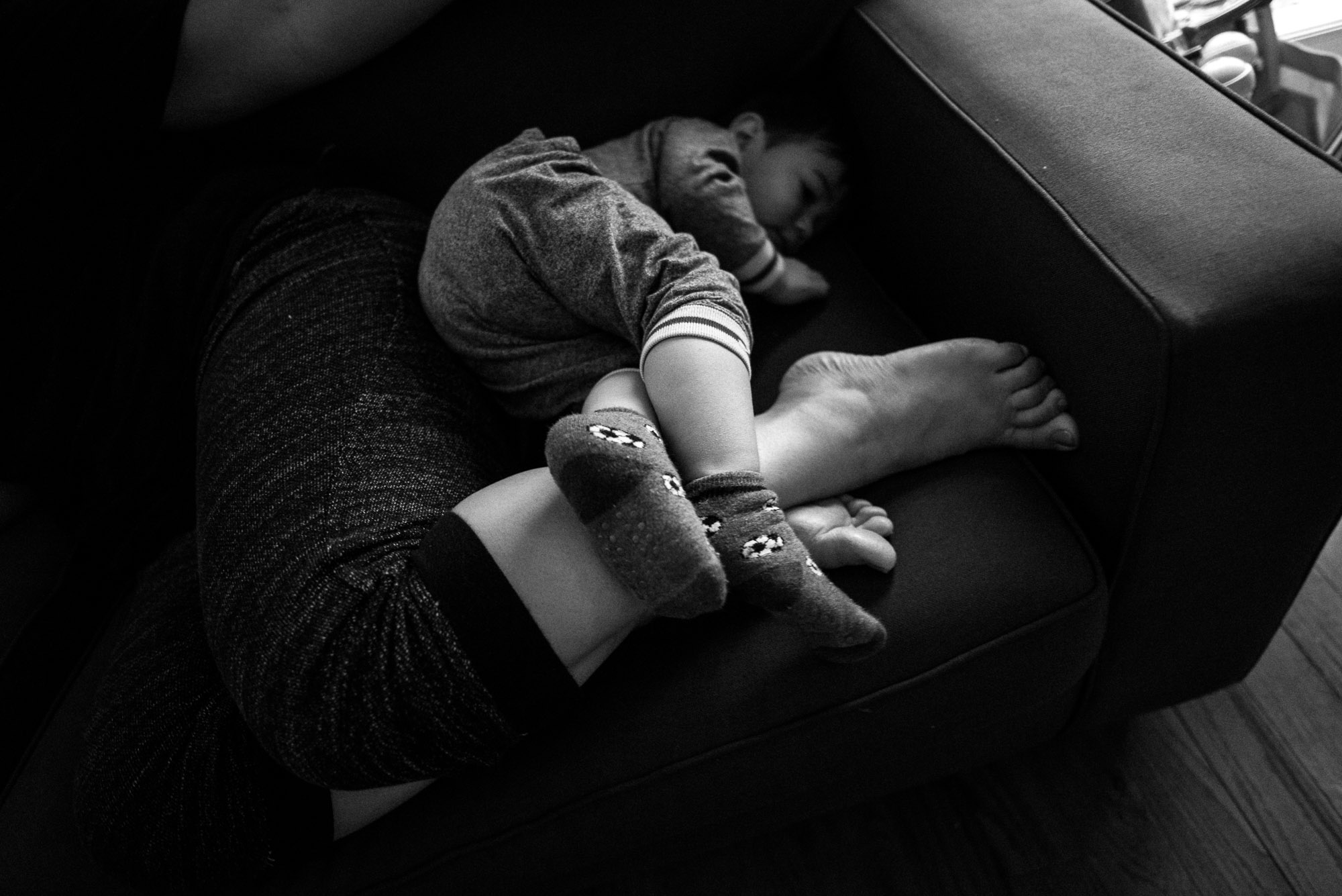 boy snuggles at his moms feet on the couch