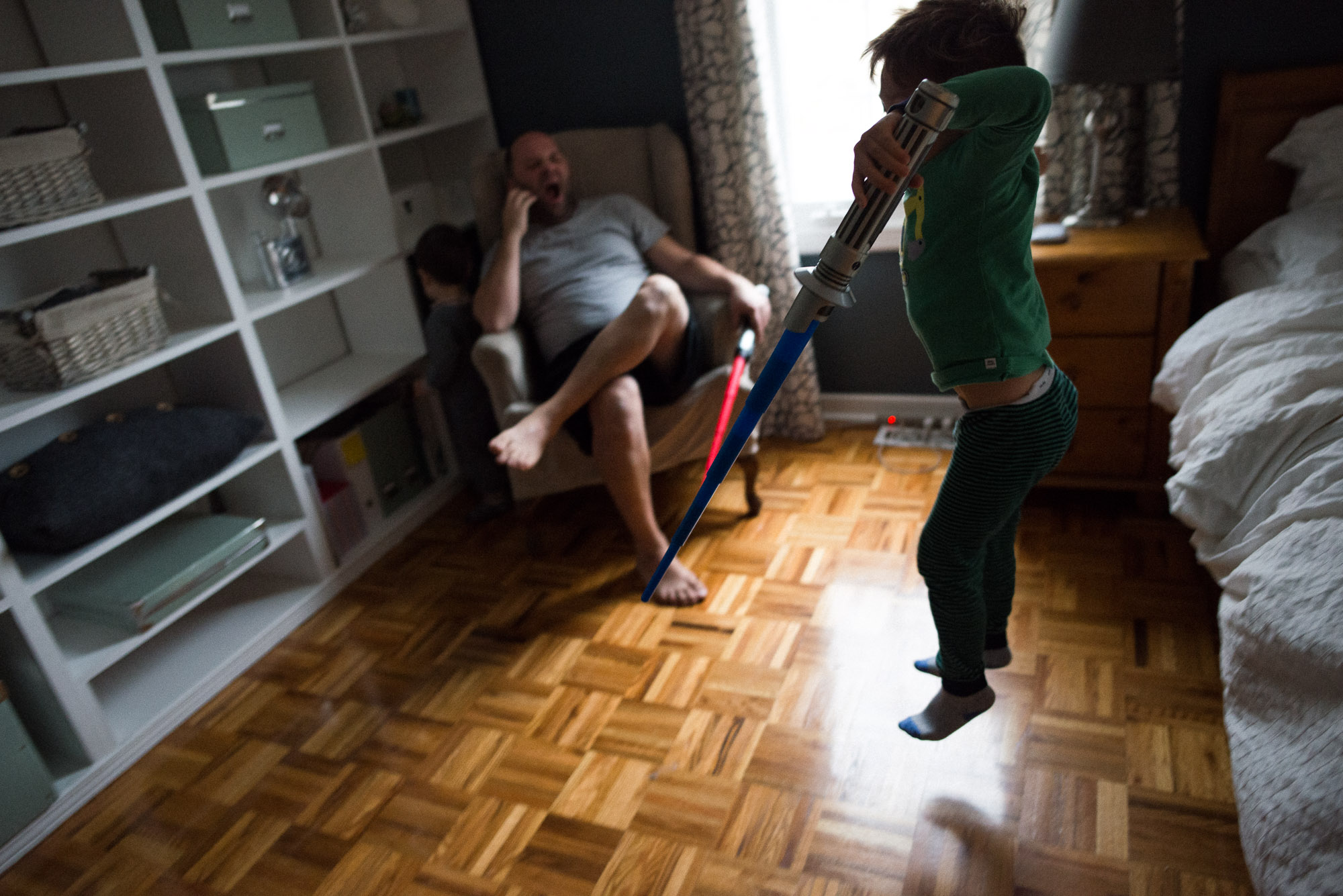 dad yawns as boy jumps from the bed