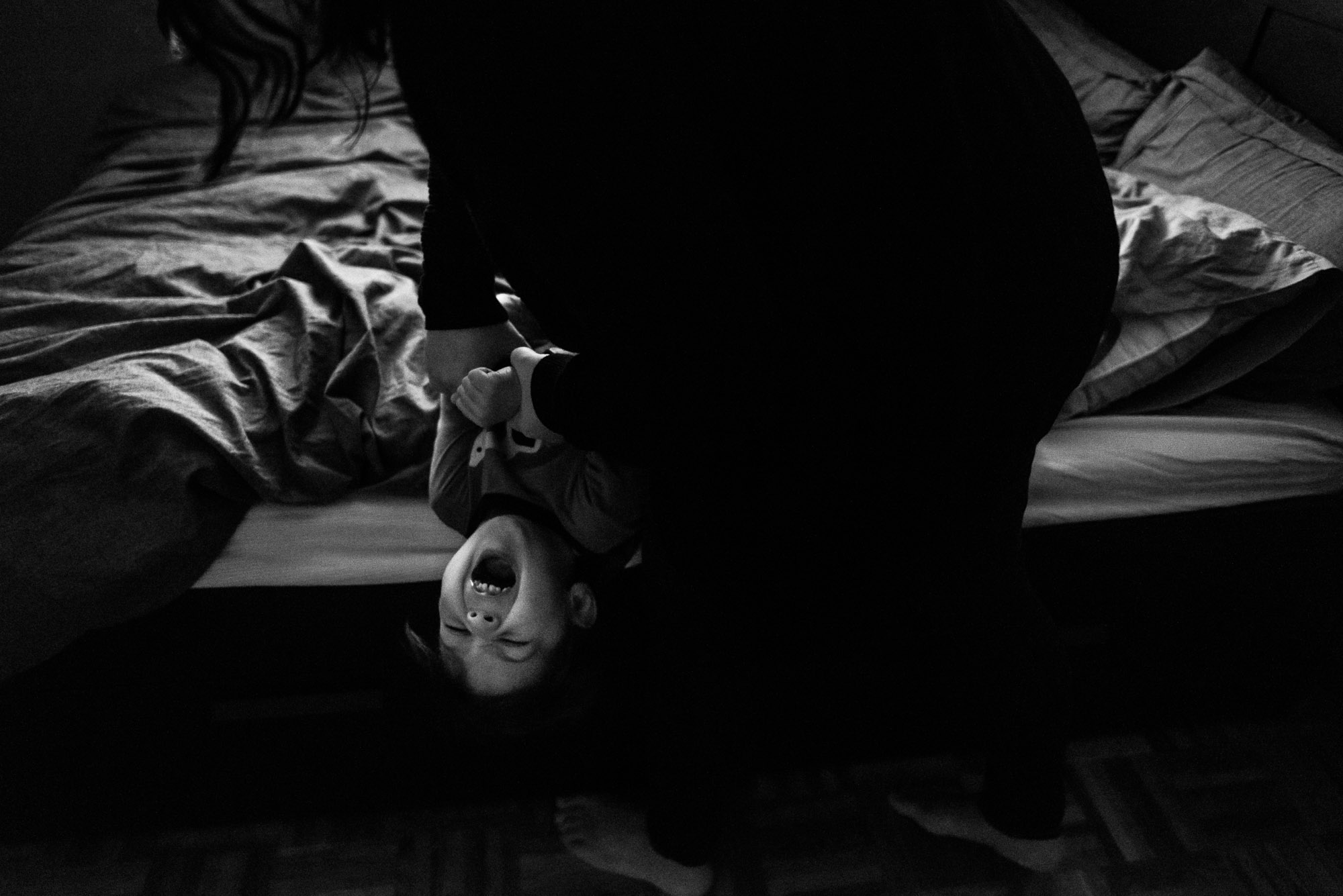 parent tickles boy on the bed