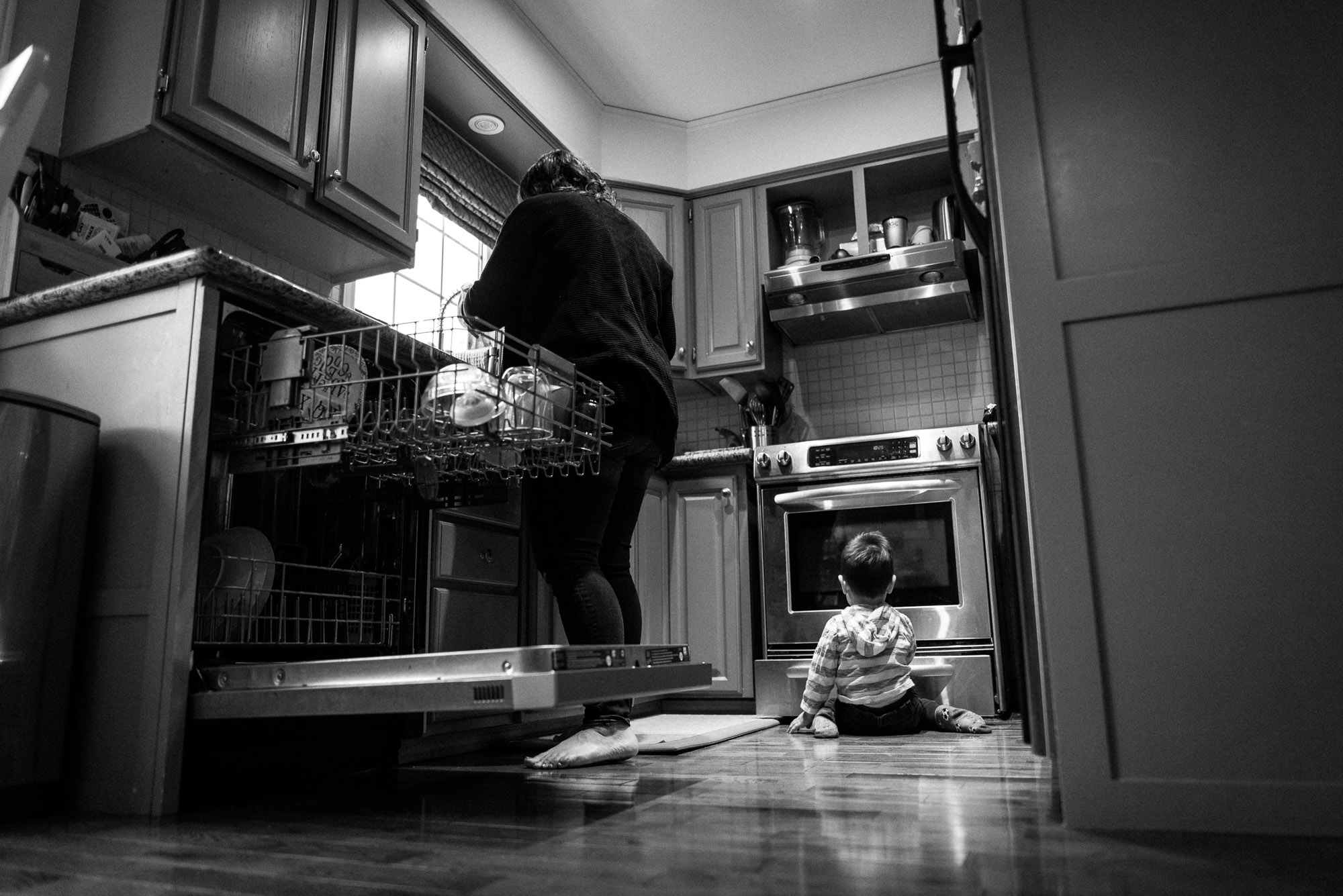 toddler plays on kitchen floor while mom cooks