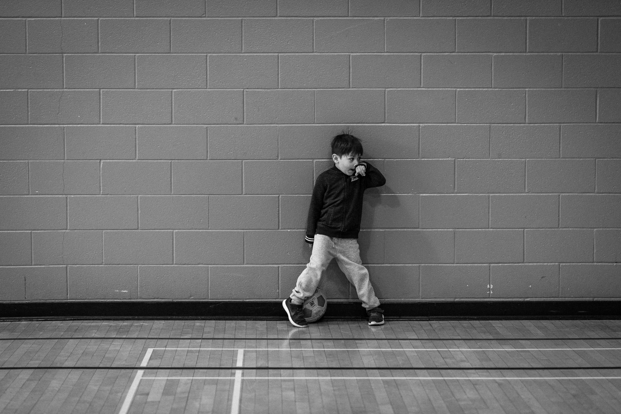 boy stands against gym wall at soccer practice