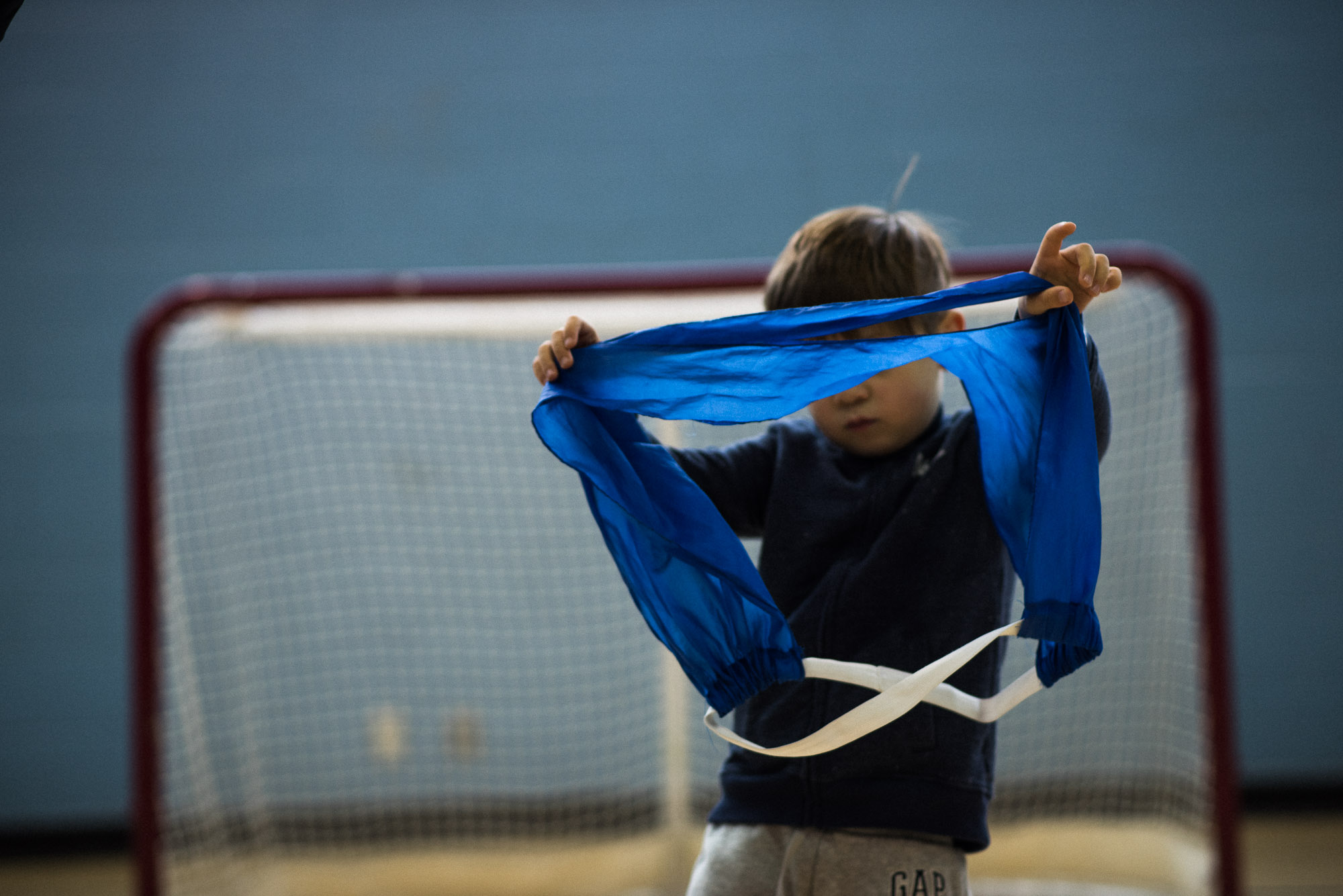 boy holds up blue soccer bib in front of his face
